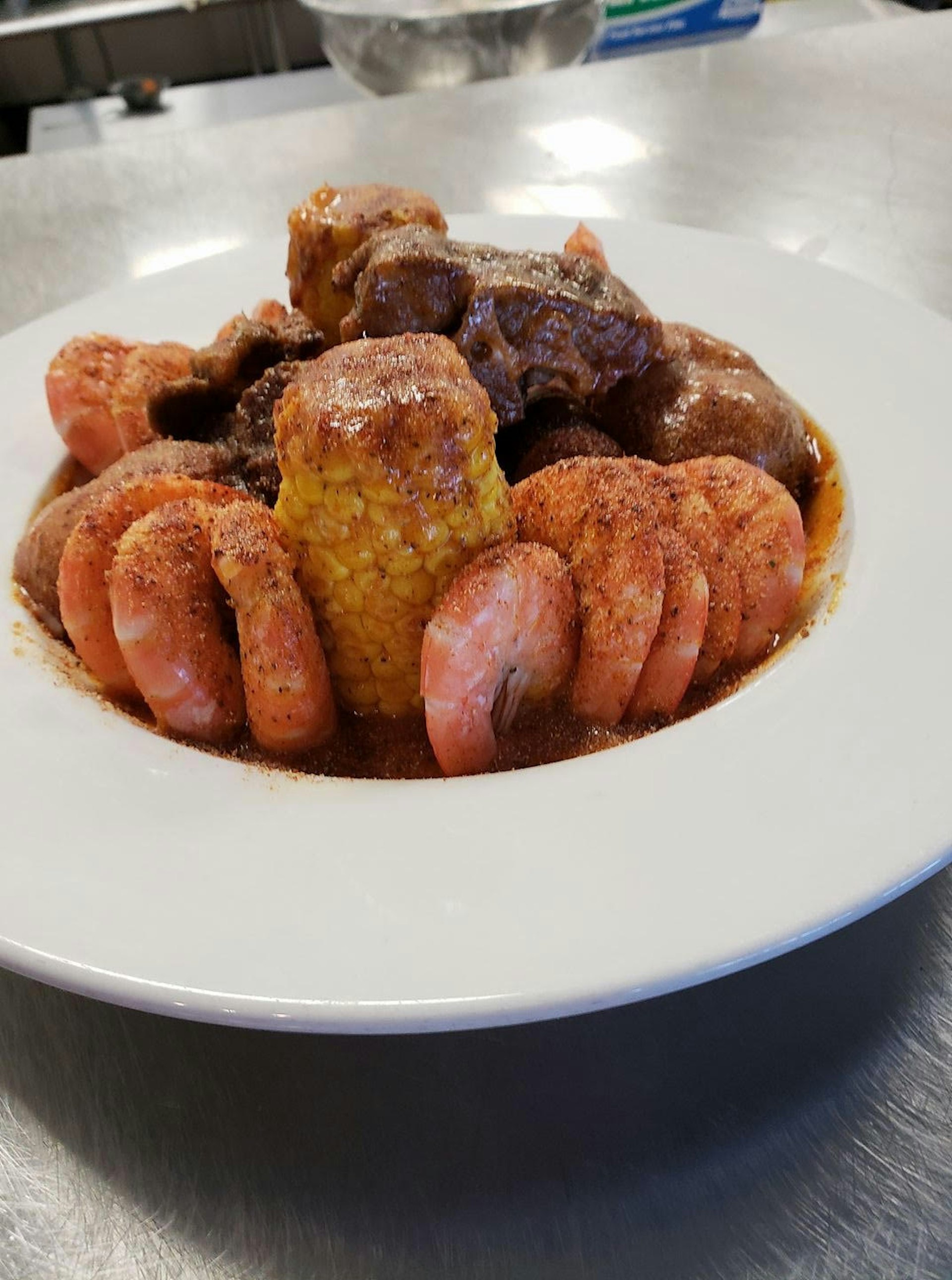 Closeup of a plate of shrimp, corn of the cob and oxtails
