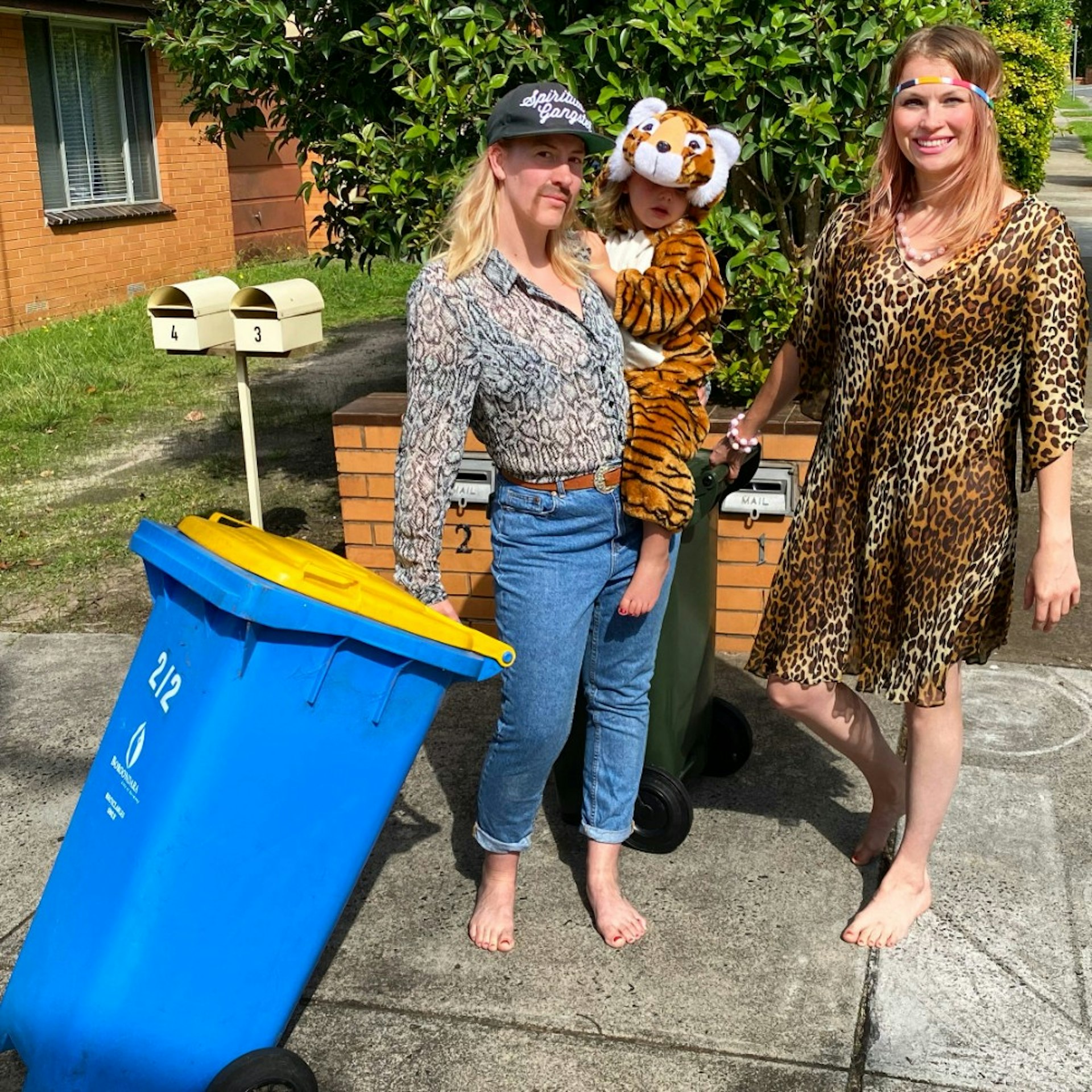 Two women and a child taking out the bin dressed like the stars of Tger King