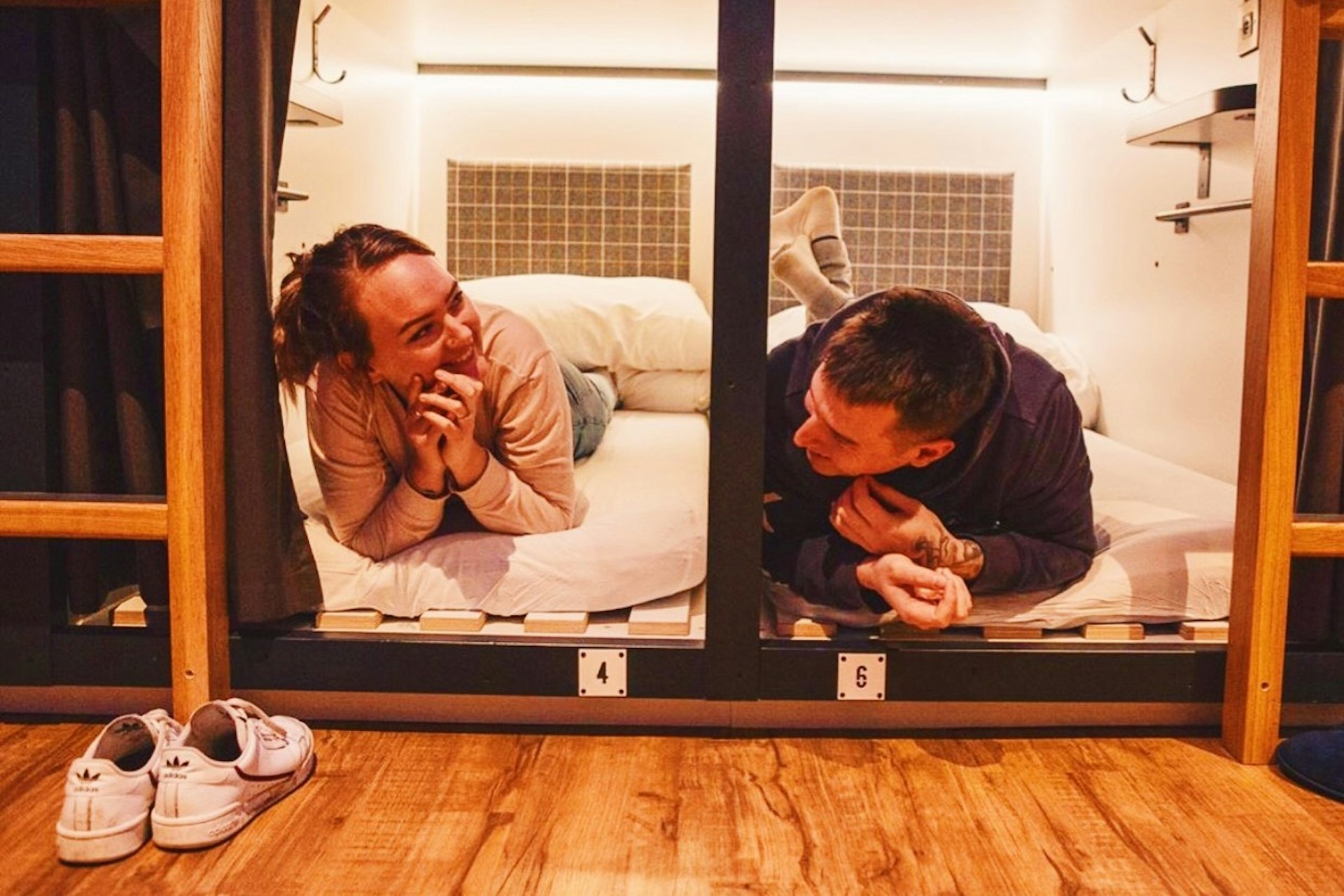 Two backpackers talking to one another in a capsule hostel 