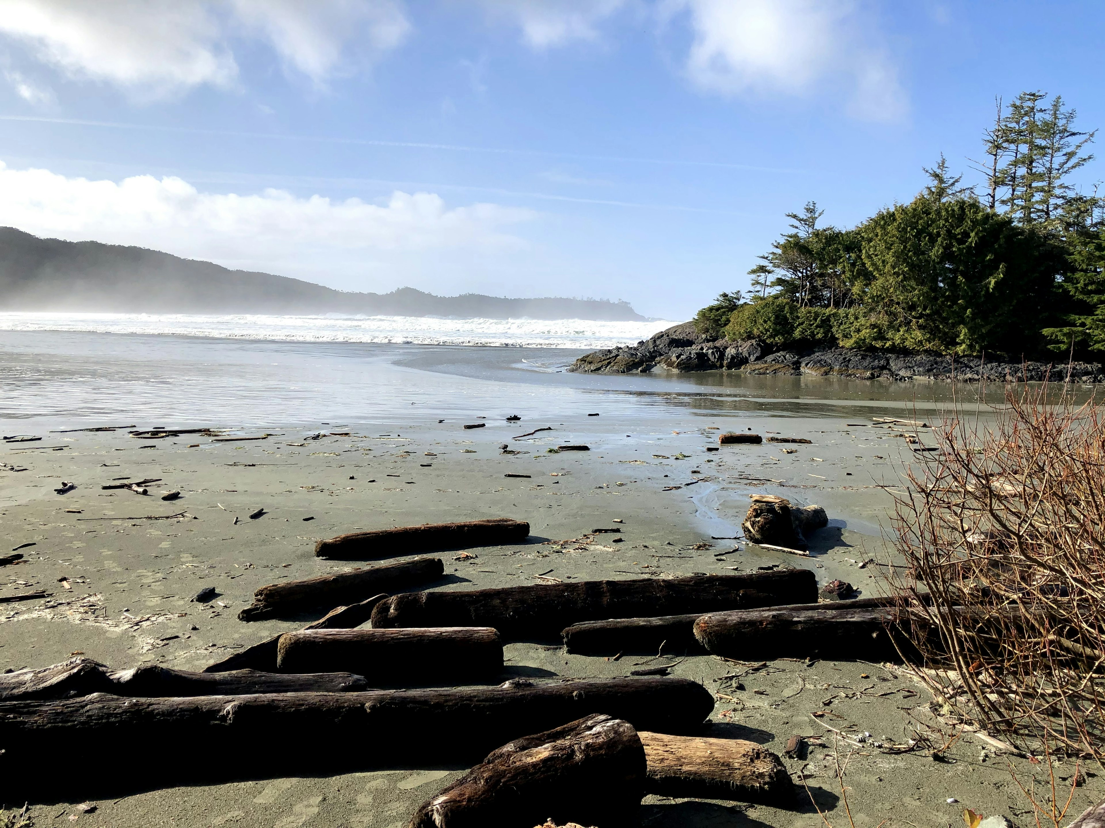 An empty beach with a rugged coastline. Sea mist is rising from the waves in the distance