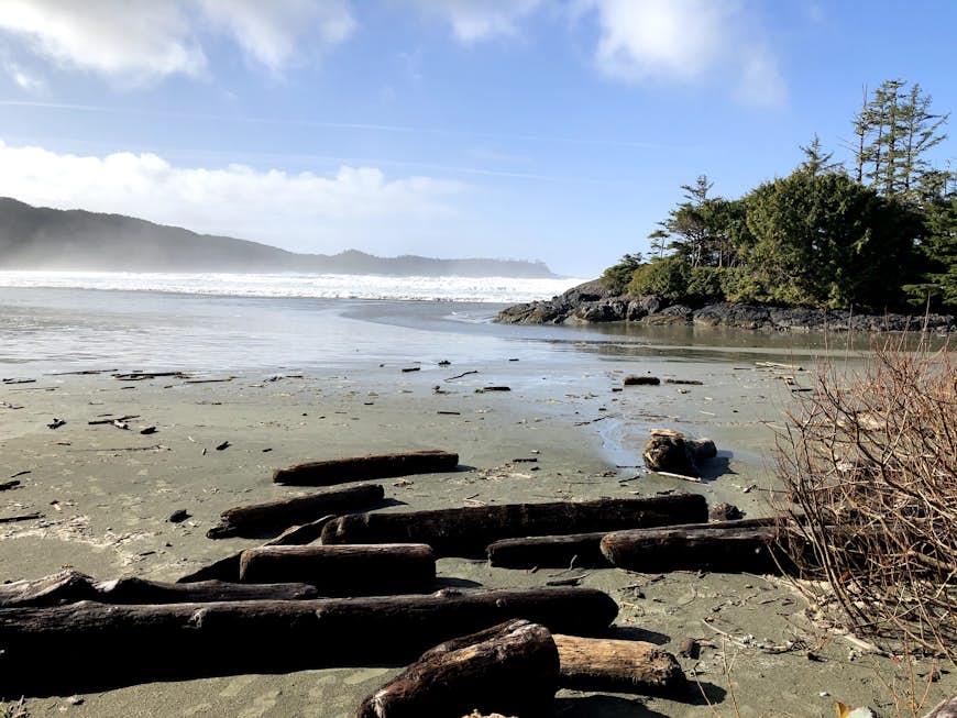 An empty beach with a rugged coastline. Sea mist is rising from the waves in the distance