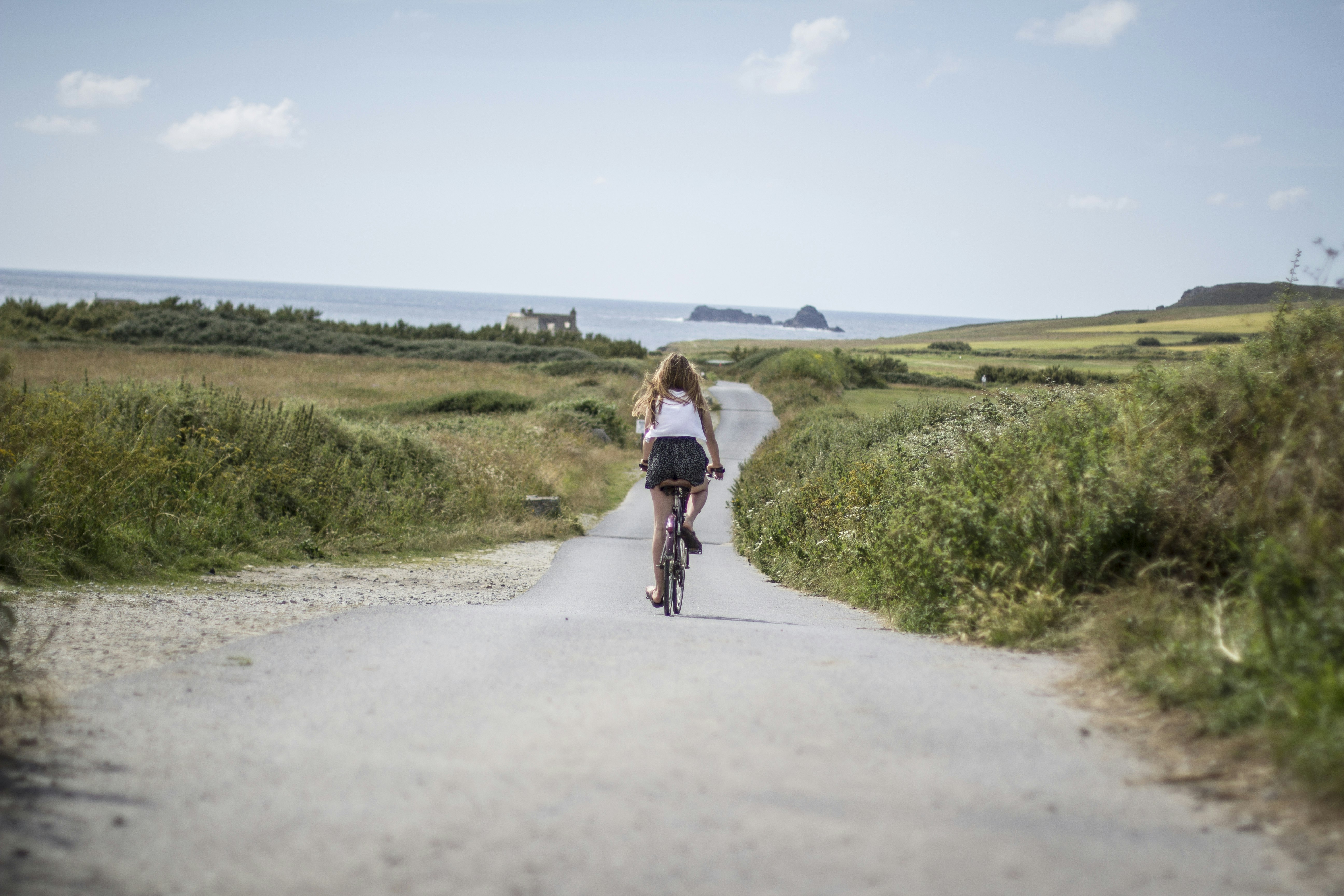 Teenage girl cycling down a road in Padstow, Cornwall 
