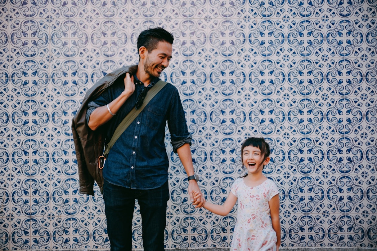 Japanese father and his preschool mixed race daughter on street of Portugal with azulejo tile wall