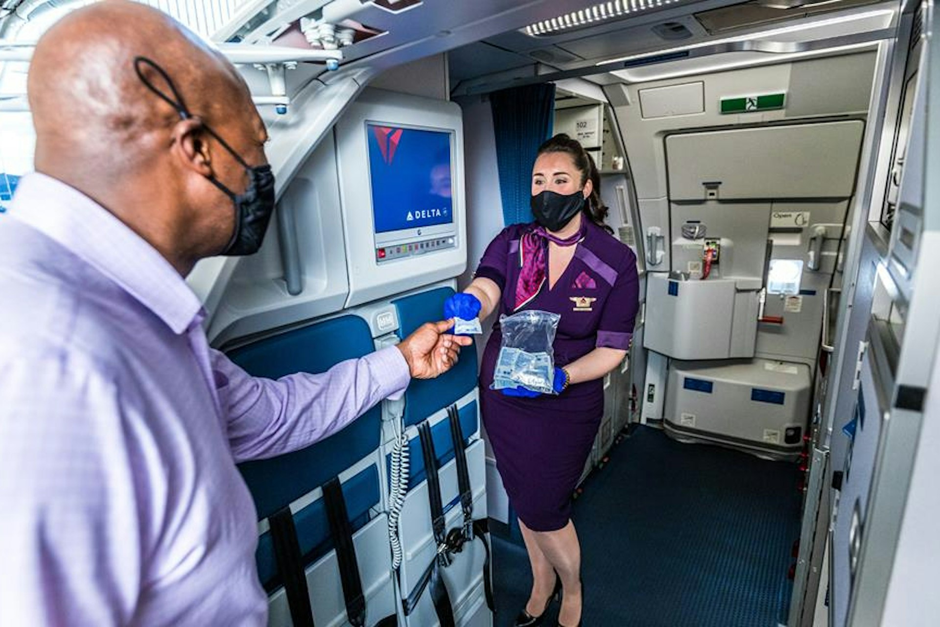 A cabin crew member greeting a passenger on a Delta flight