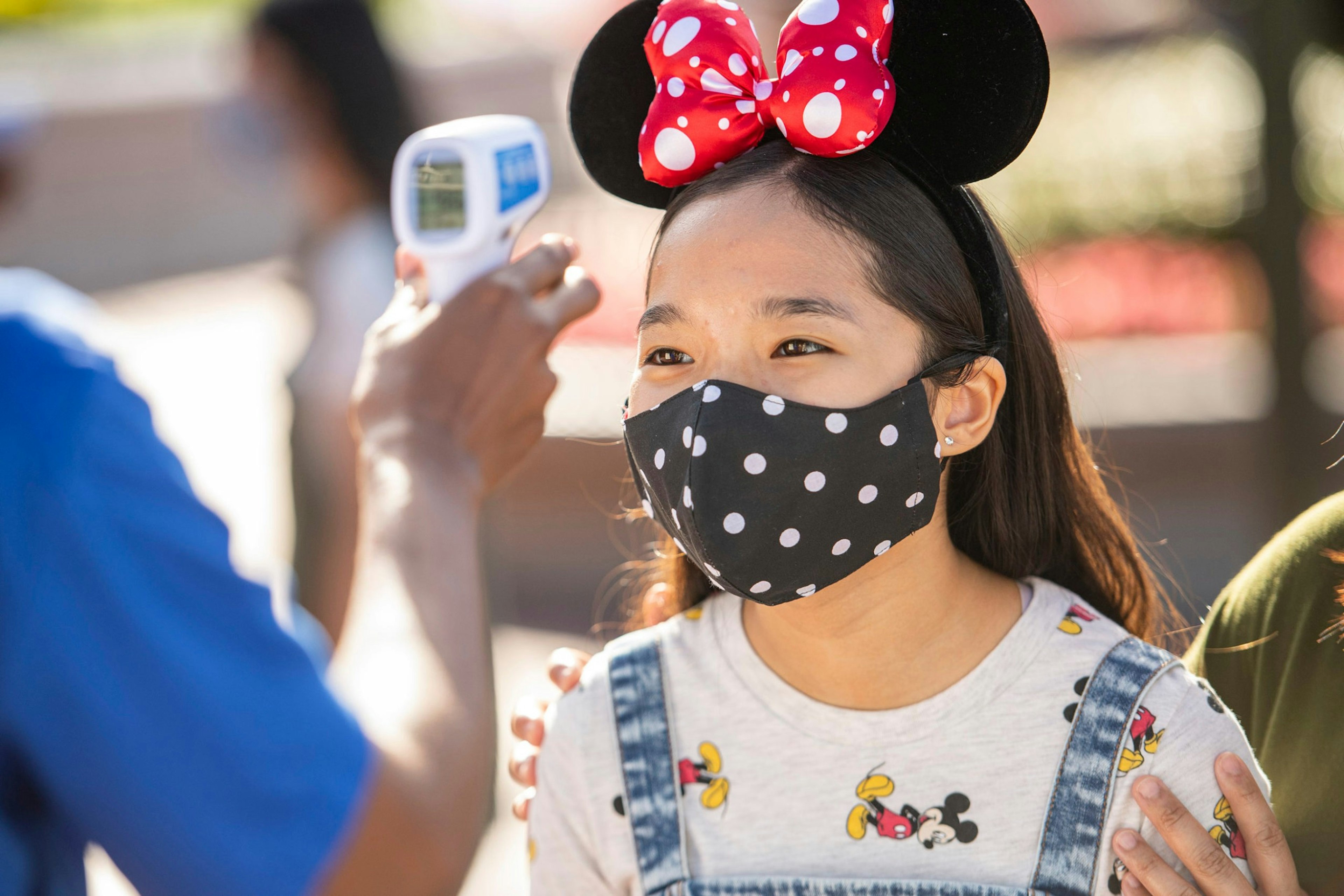 A child wearing a mask having her temperature taken at Walt Disney World