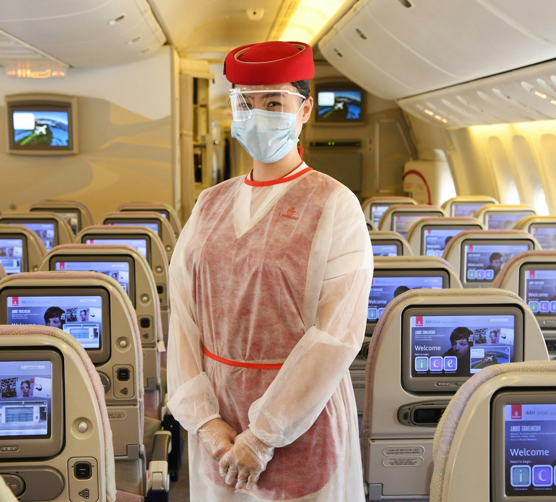 A female Emirates cabin crew member wearing a medical mask