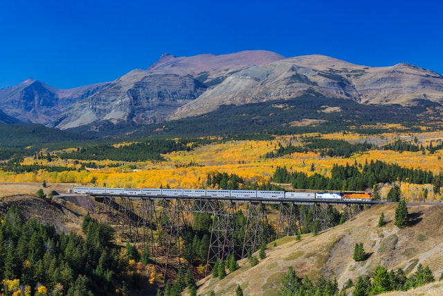 A passenger train crossing over trestle bridge in Glacier National Park