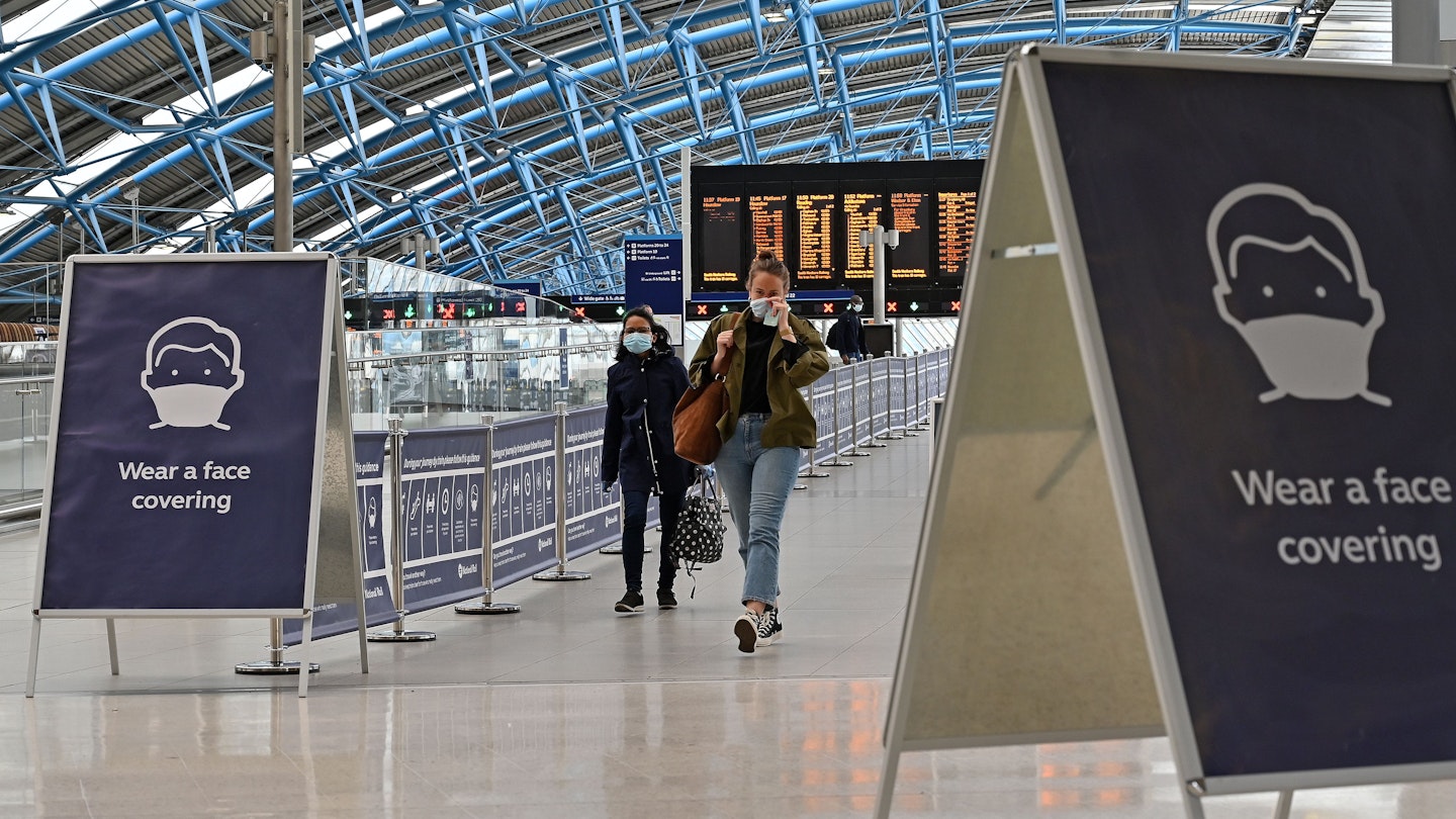 A sign tells passengers to 'wear a face covering' at Waterloo train station in central London , on June 8, 2020, as the UK government's planned 14-day quarantine for international arrivals to limit the spread of the novel coronavirus COVID-19 begins. - Masks will be compulsory on public transport in England from next week to prevent the spread of the coronavirus, transport minister Grant Shapps said. "As of 15th June, face coverings will be mandatory on public transport," he said at a daily briefing on the government's response to the coronavirus outbreak. (Photo by JUSTIN TALLIS / AFP) (Photo by JUSTIN TALLIS/AFP via Getty Images)