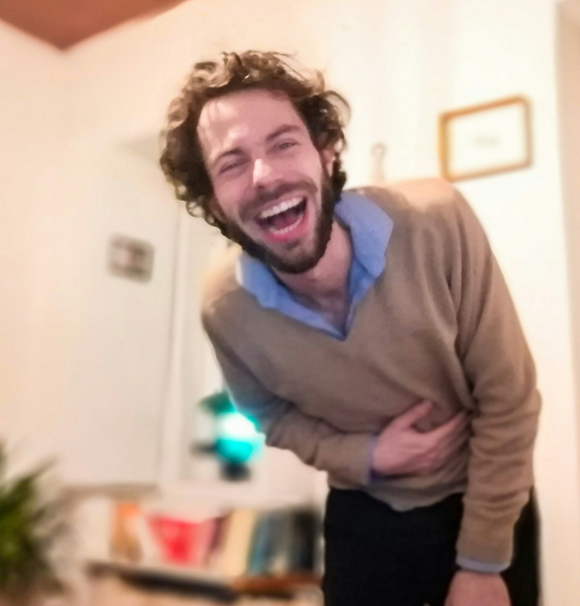 A man in a brown sweater laughing