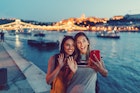 Two women in Budapest waving with hand to say hello on video call