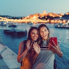 Two women in Budapest waving with hand to say hello on video call