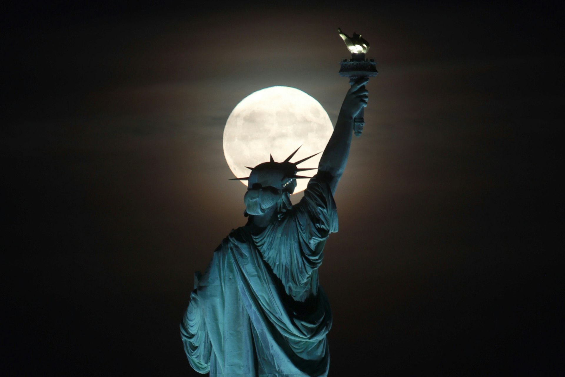 The Statue of Liberty in front of a full moon