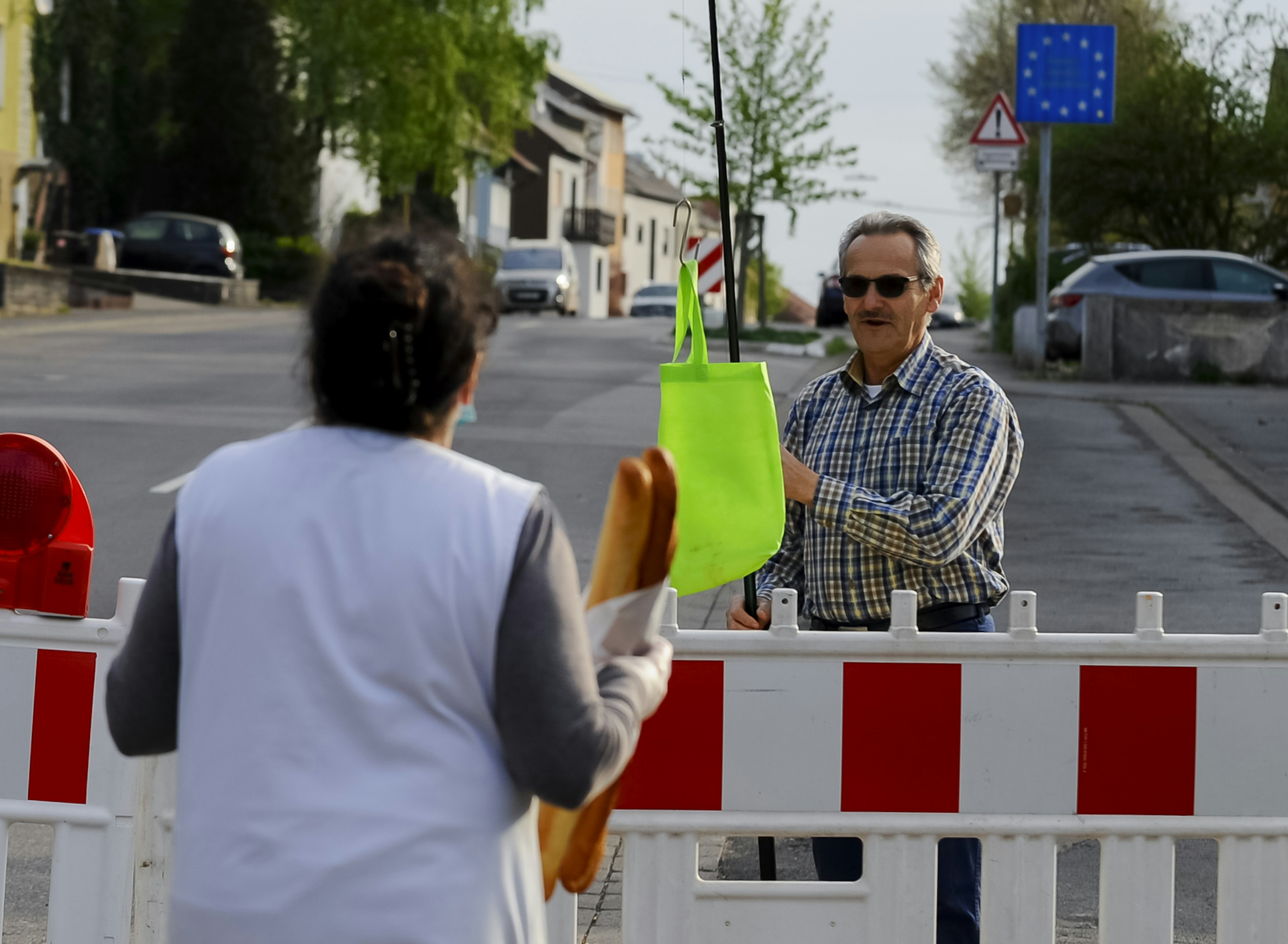 German man uses fishing rod to collect bread from his baker at the closed border crossing