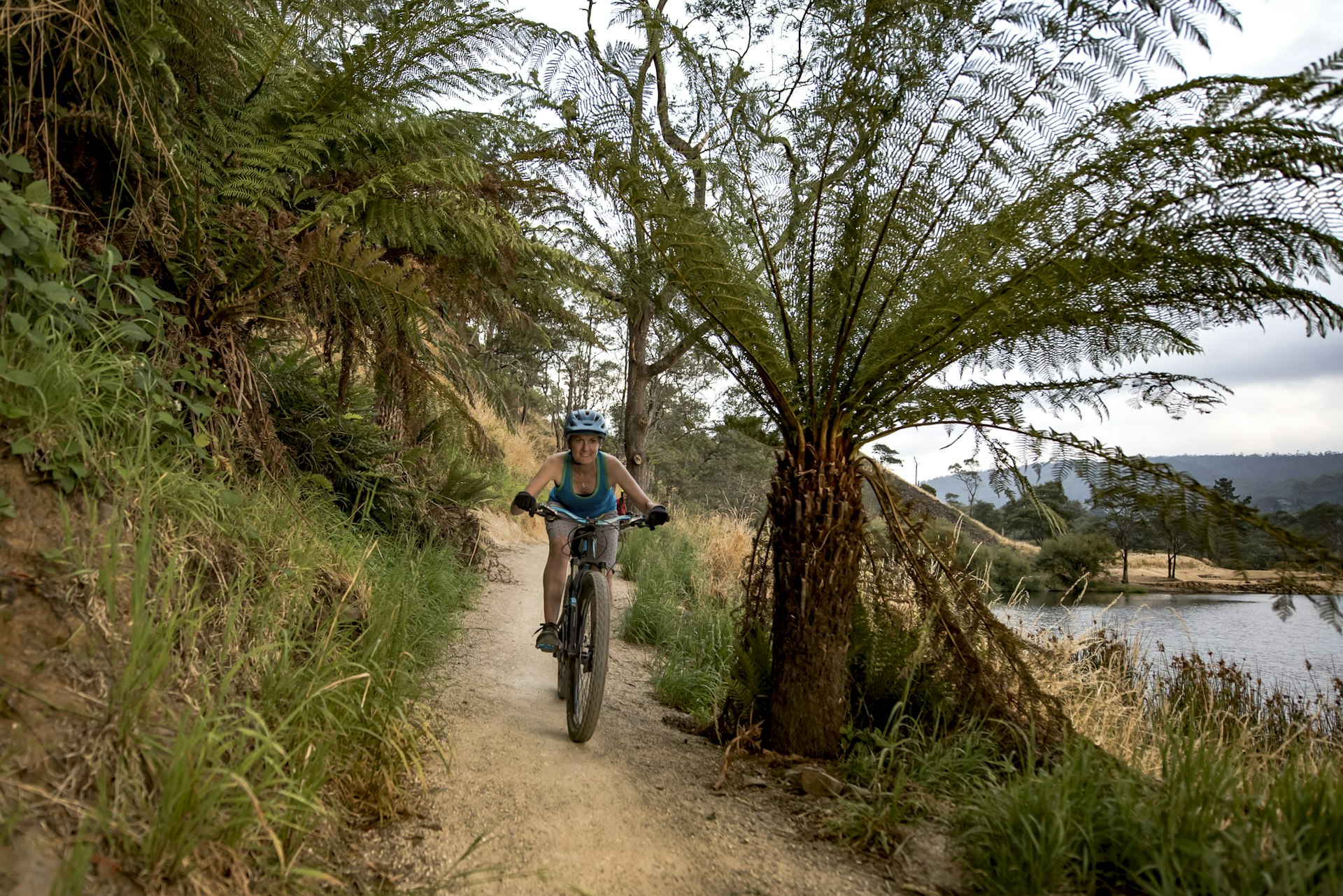 A woman rides a mountain bike on a path by a lake