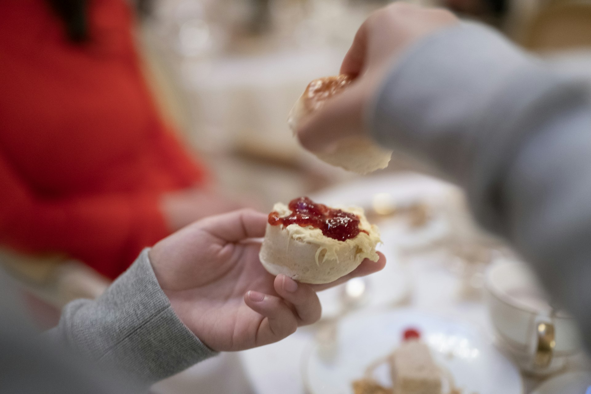 Child spoons clotted cream and jam on to a scone