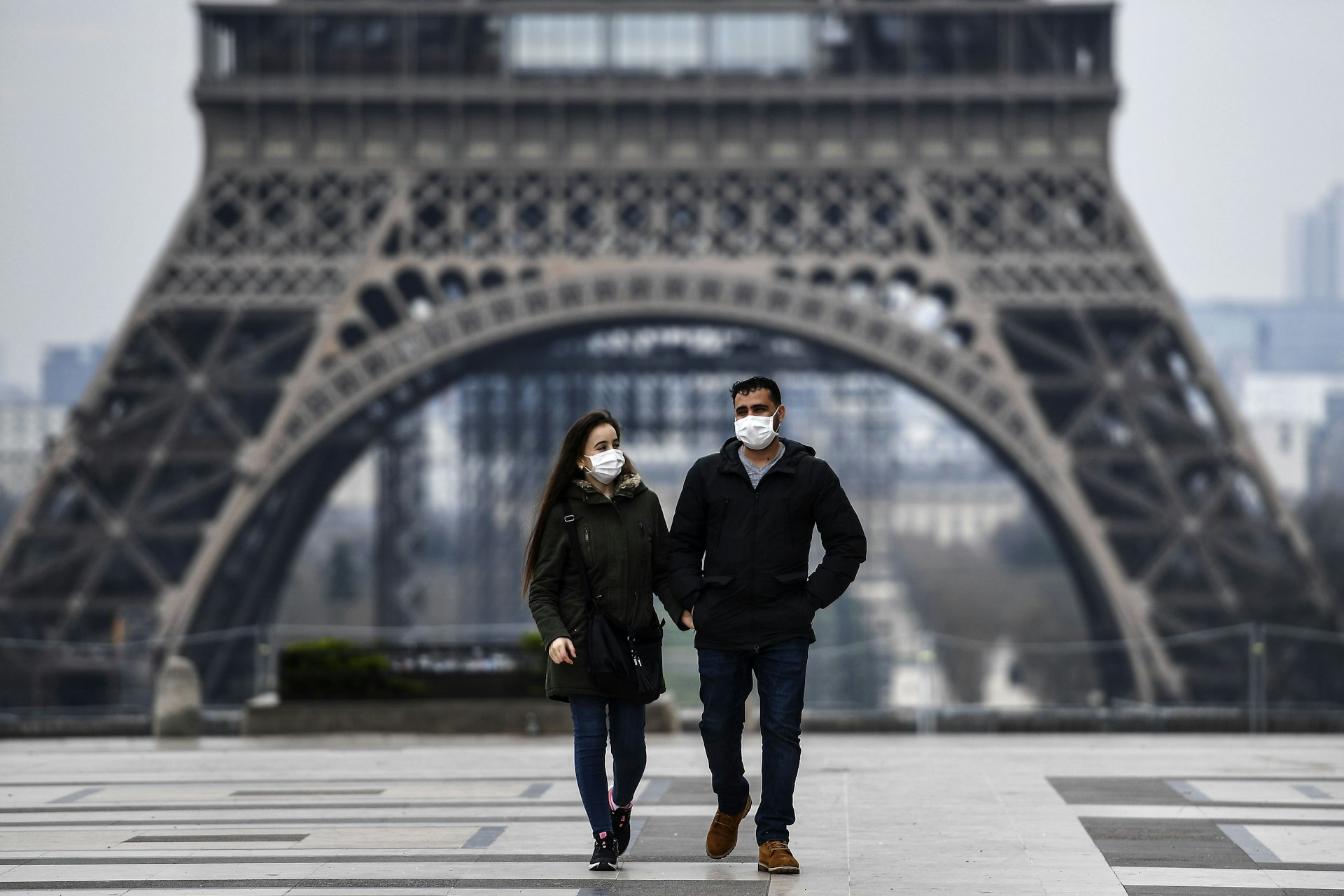 A couple wearing protective mask walks by the Esplanade du Trocadero square near the Eiffel Tower in Paris