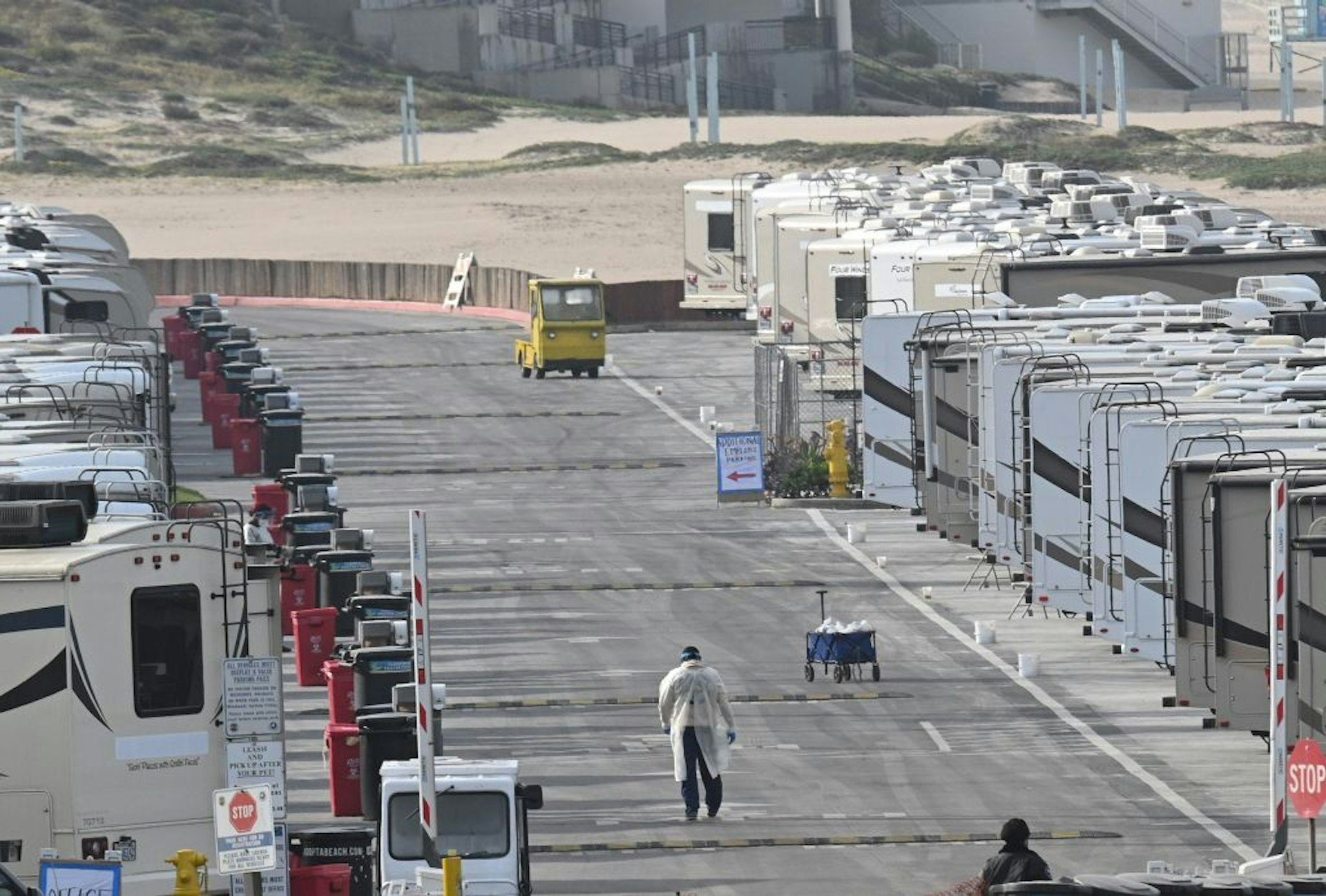 Medical staff walk among RV campers in a beachside parking lot being used as an isolation zone for people with COVID-19, on March 31, 2020, at Dockweiler State Beach in Los Angeles, California. 