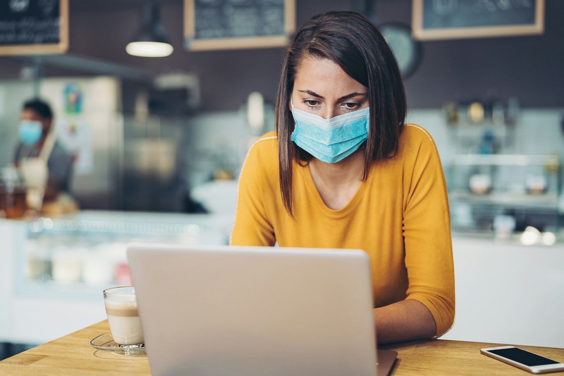 Worried woman with a face mask looking at a laptop