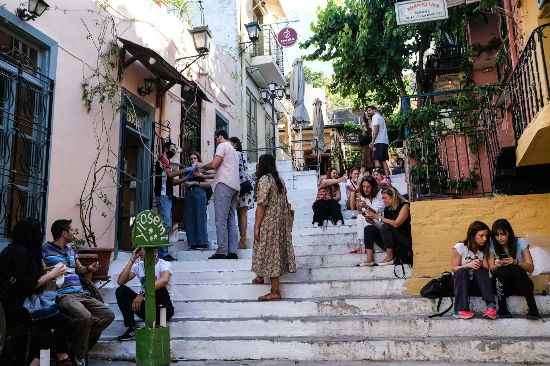 Tourists and locals mill about outside of a cafe opened for take away business in the Plaka district on May 23, 2020 in Athens, 