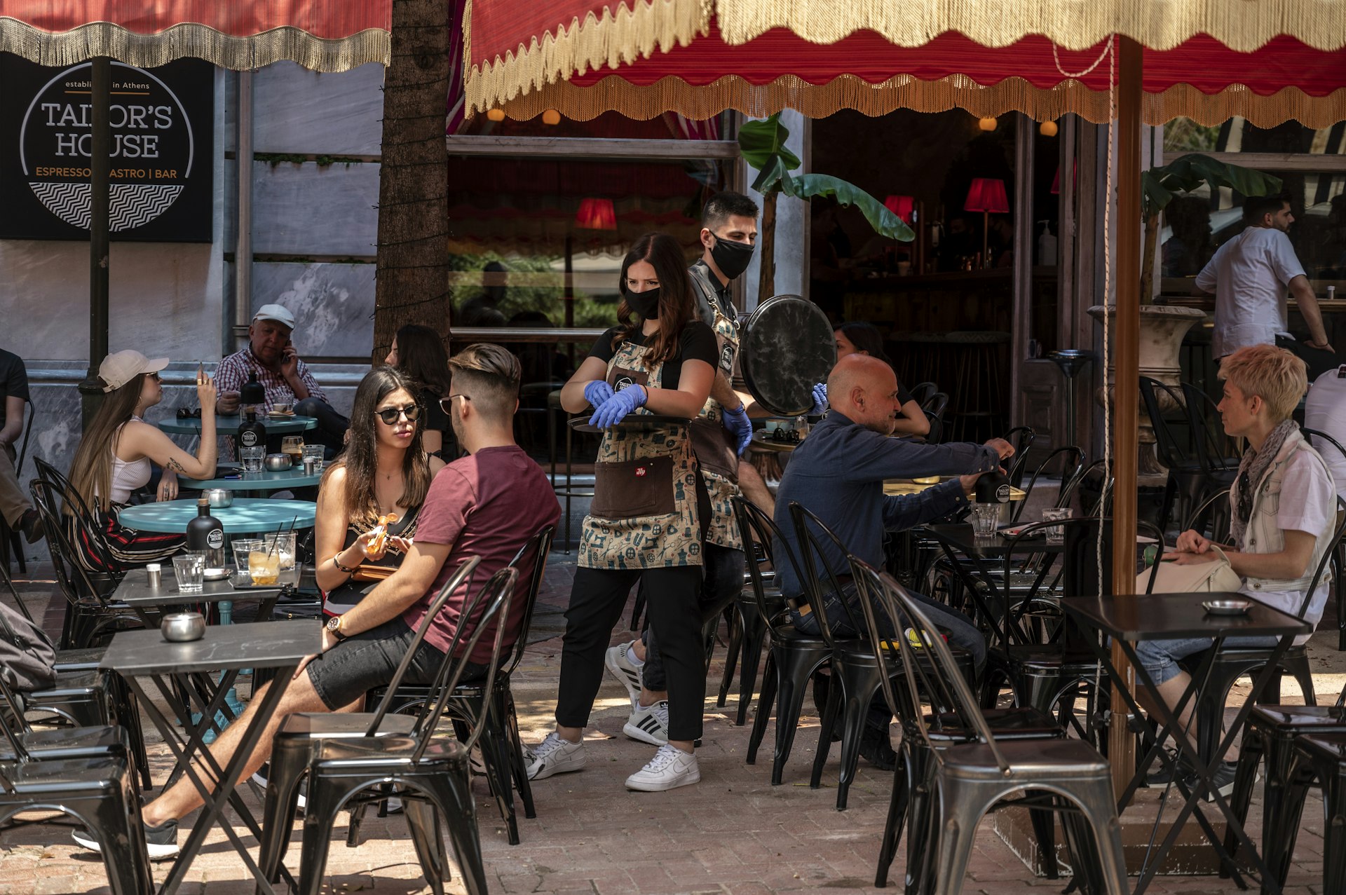 A waitress with a face mask and disposable gloves takes an order in a cafe in Athens