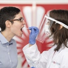 29 June 2020, Hessen, Frankfurt/Main: For demonstration purposes, an employee of the Centogene company takes a throat swab from a colleague. In the future, people will be able to be tested for the corona virus within a few hours at Germany's first "Airport Corona Test" centre. Photo: Boris Roessler/dpa (Photo by Boris Roessler/picture alliance via Getty Images)