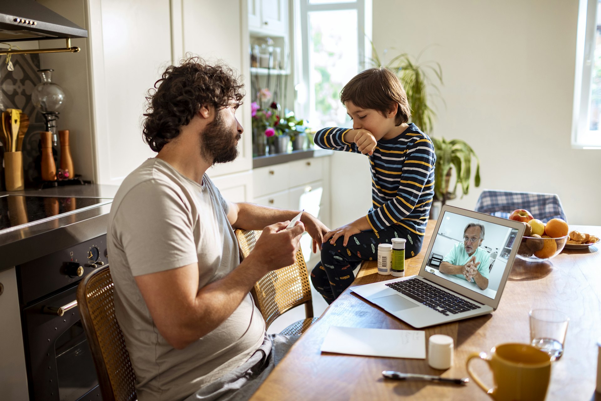 Close up of a father with his son consulting with their doctor over a video call on the laptop. 