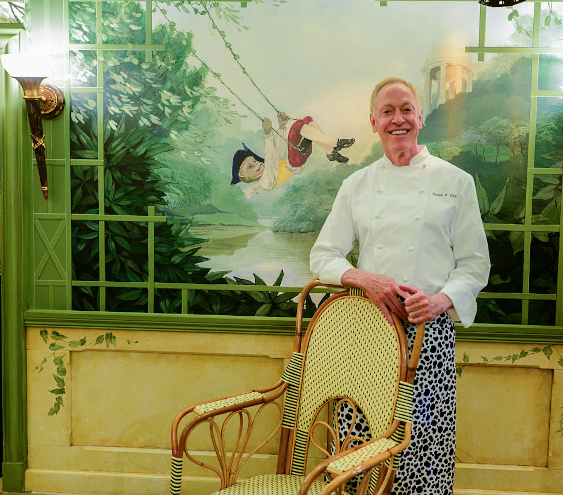 Chef/Owner Patrick OConnell stands in the dining room at The Inn At Little Washington in front of a whimsical mural of a young boy on a swing