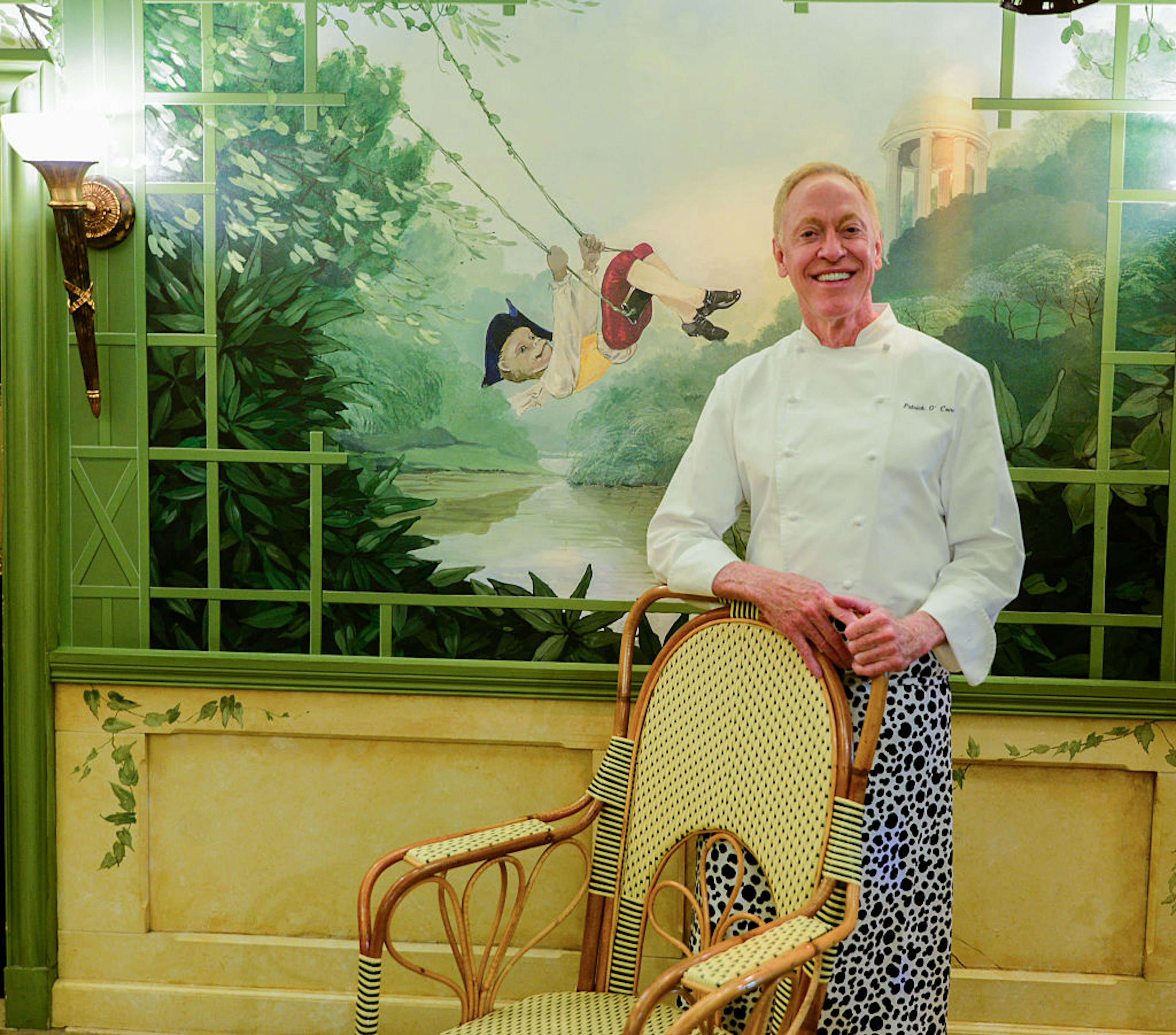 Chef/Owner Patrick O'Connell stands in the dining room at The Inn At Little Washington in front of a whimsical mural of a young boy on a swing