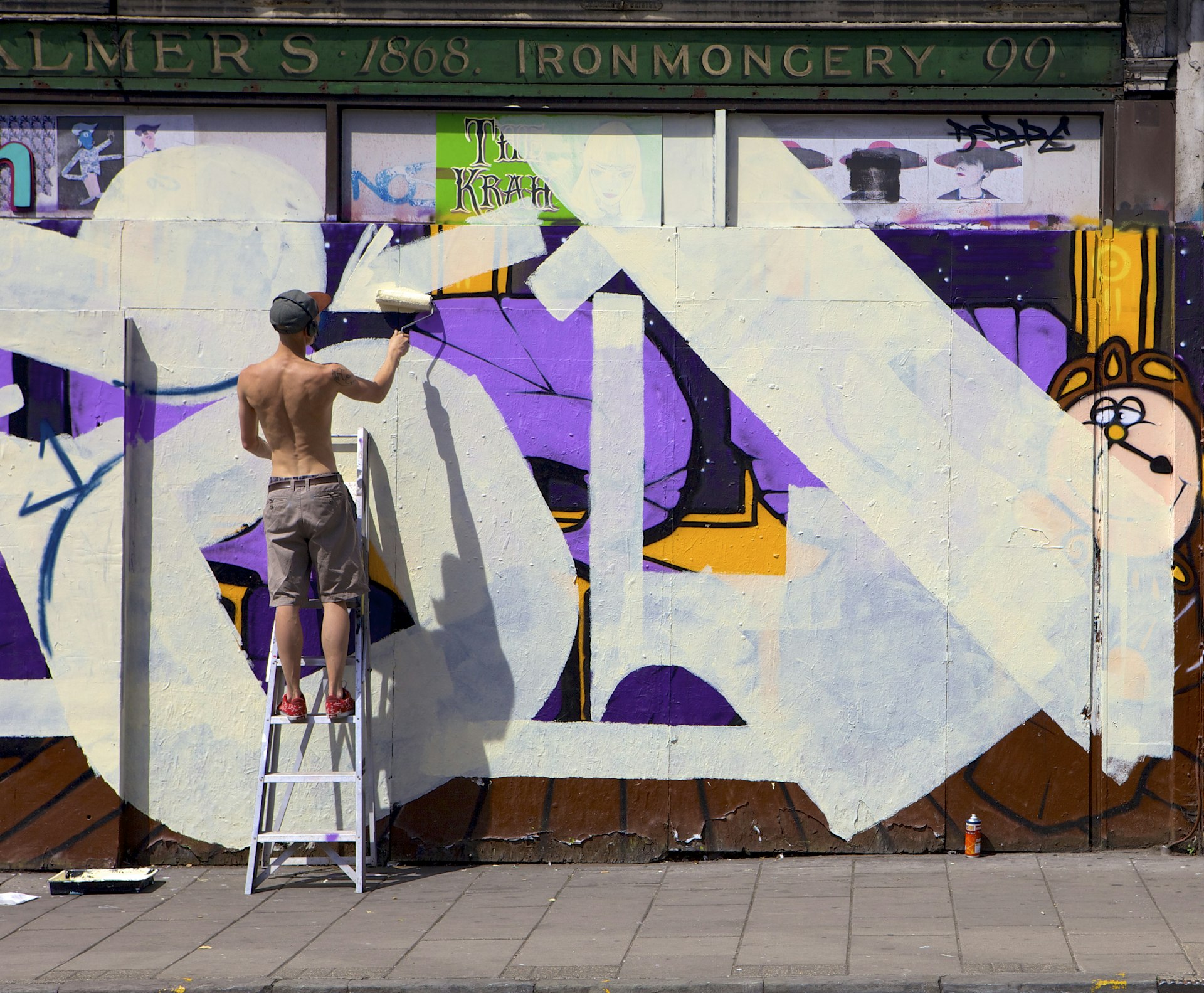 A street artist painting over an old shop front