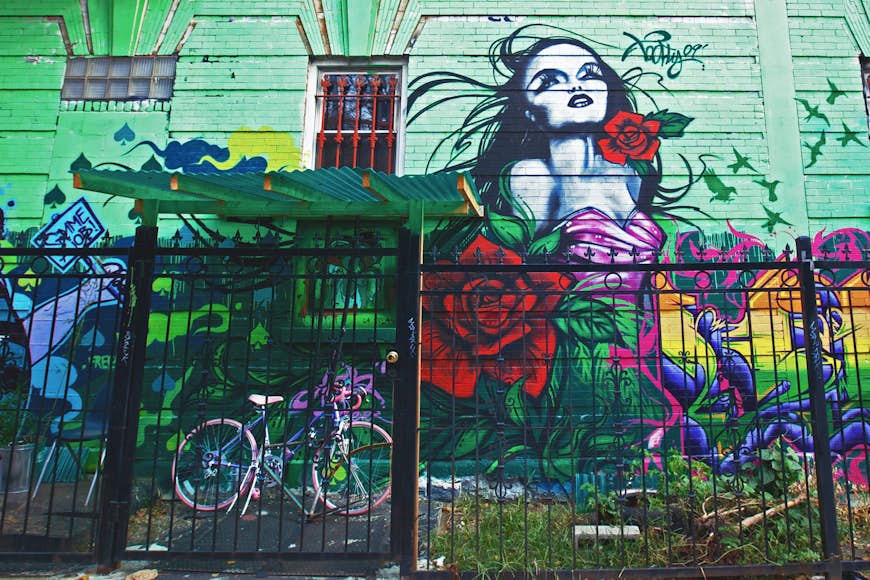 Pink bike behind the fence near painted mural in Williamsburg New York City