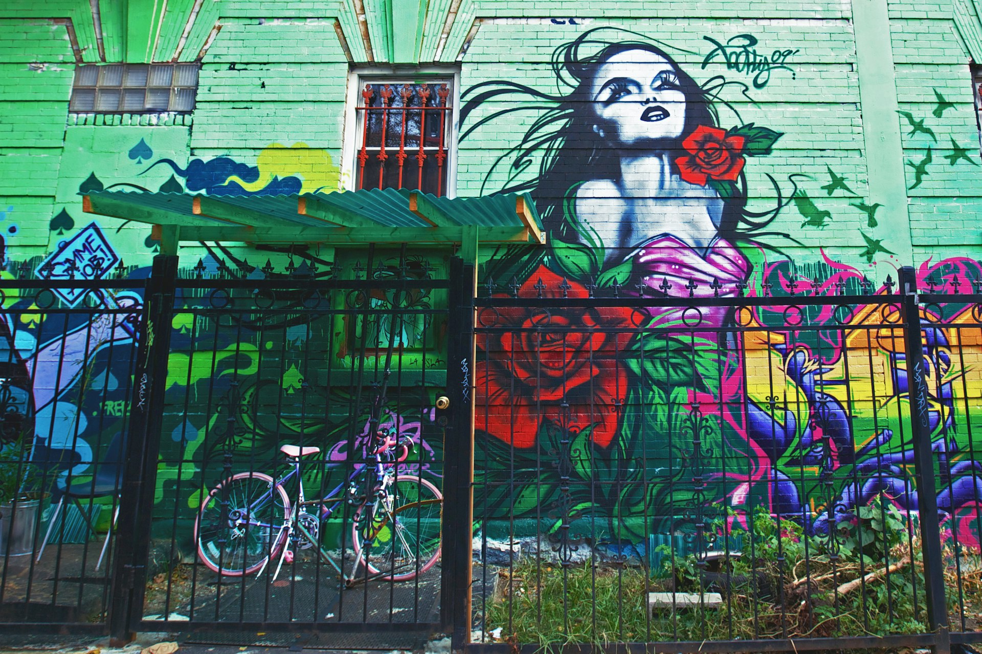 Pink bike behind the fence near painted mural in Williamsburg New York City