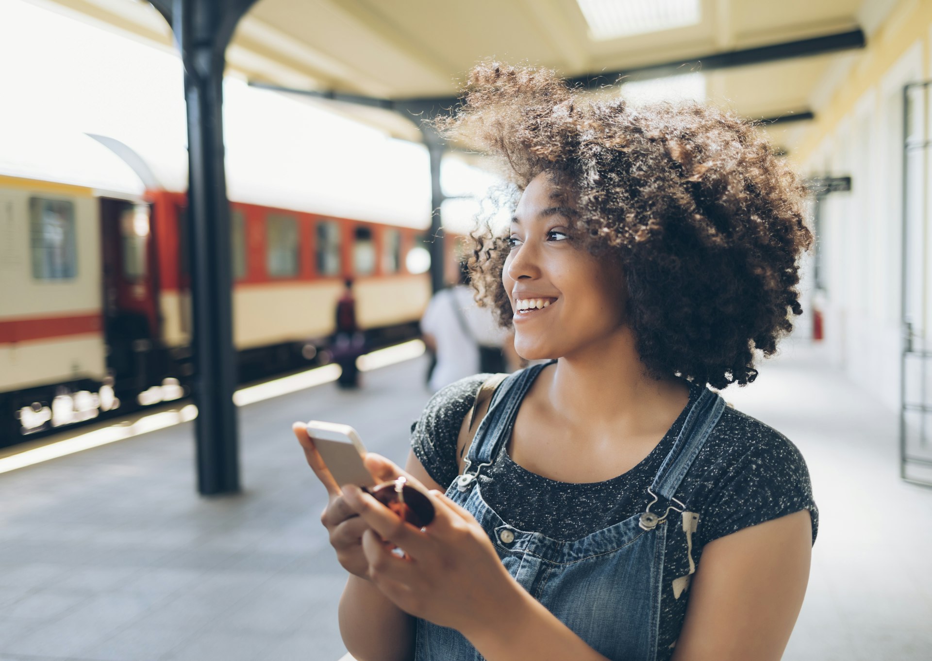 Smiling woman using smart phone on station
