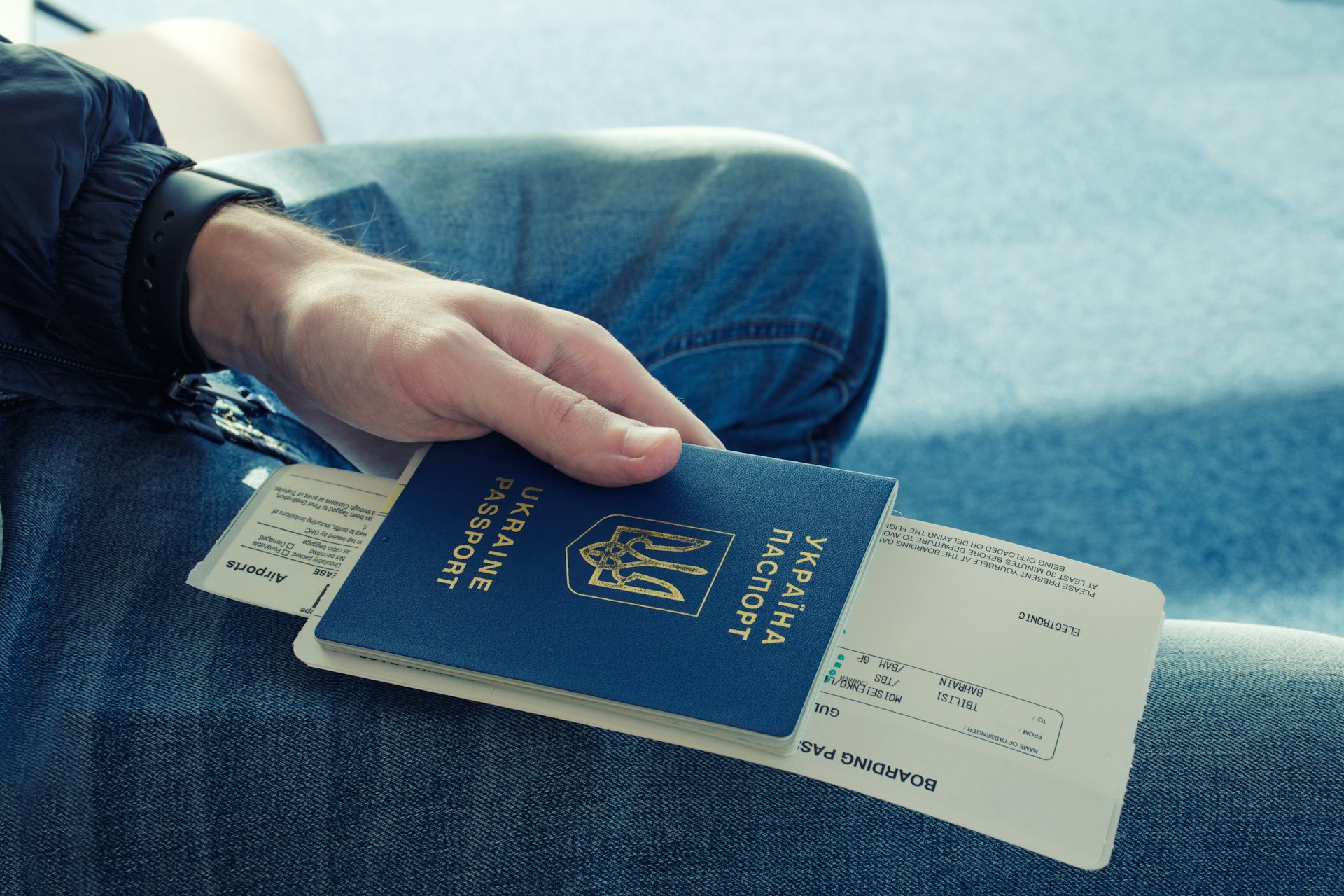 A passenger's hand holding passport and ticket