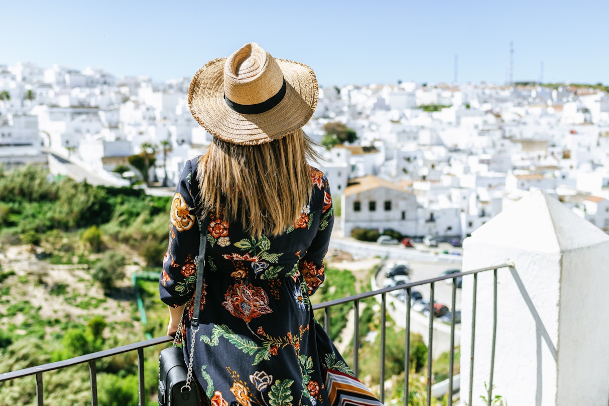 Fashionable woman on roof terrace looking at the white buildings of Vejer de la Frontera.