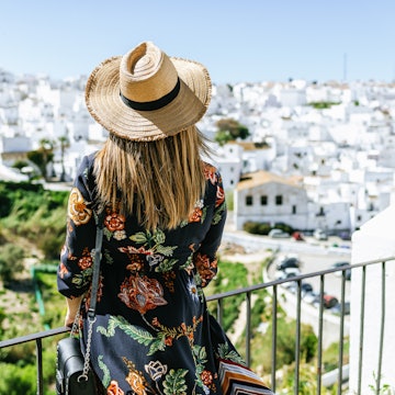 Fashionable woman on roof terrace looking at the white buildings of Vejer de la Frontera.