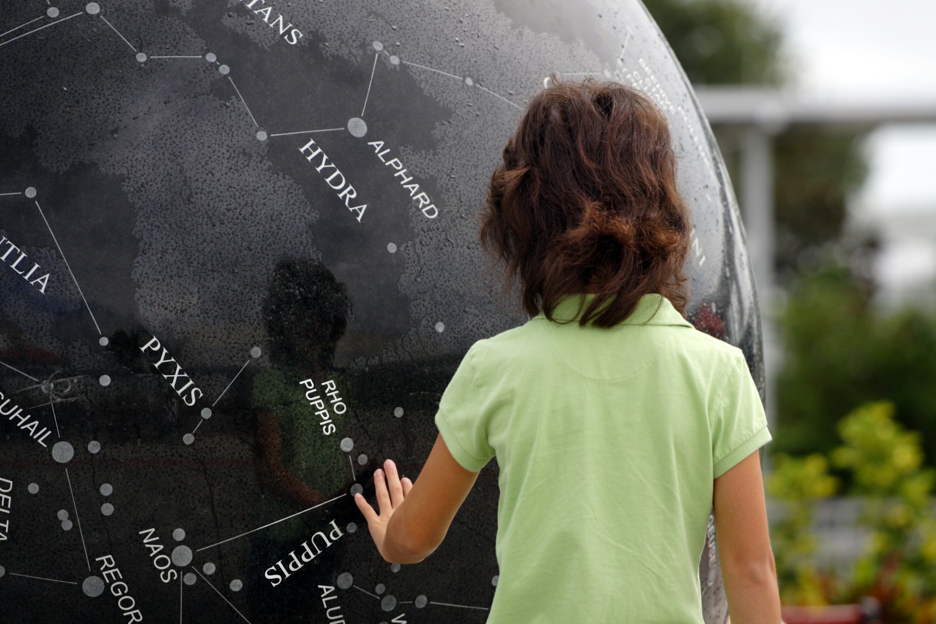 Girl putting her hand on a sculpture with a map of stars at the Kennedy Space Center. 