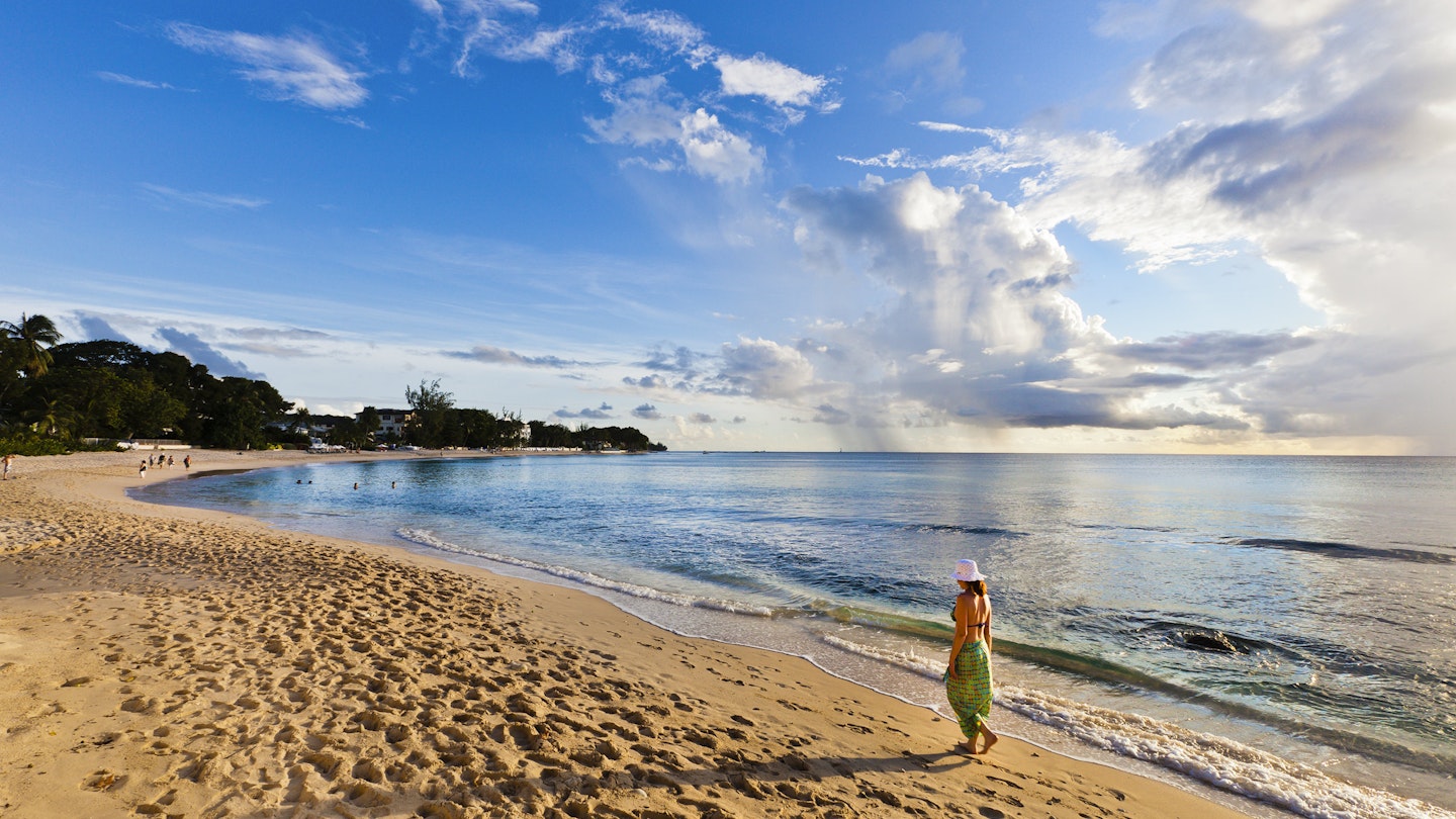 Woman walking on the beach of Paynes Bay at sunset. Surrounded by a beautiful stretch of sand, this is one of the most popular beach on the west coast of Barbados. Canon EOS 5D Mark II
