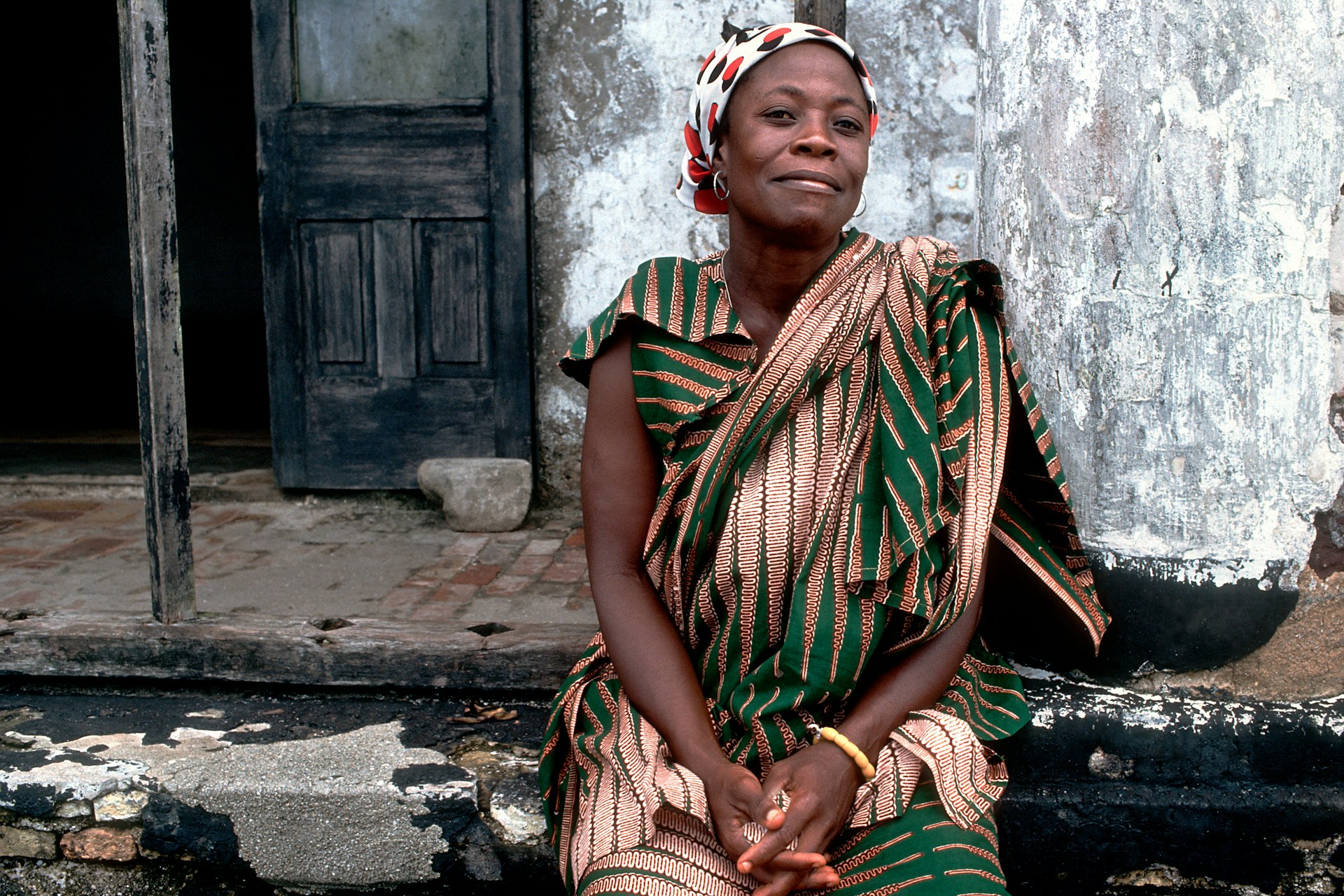 A Ghanaian woman poses for a photo close to Elmina Castle in Ghana.