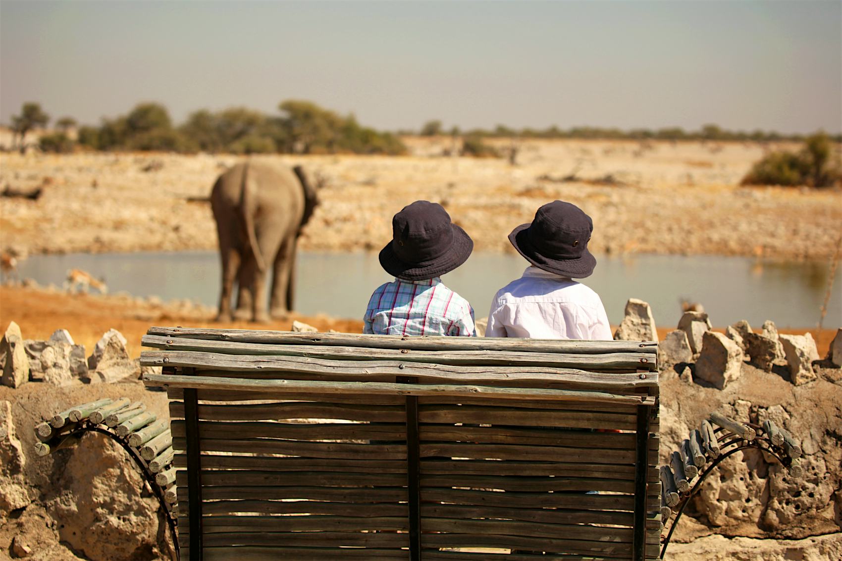 Two children are watching an elephant at the Okaukuejo waterhole in Etosha National Park in Namibia