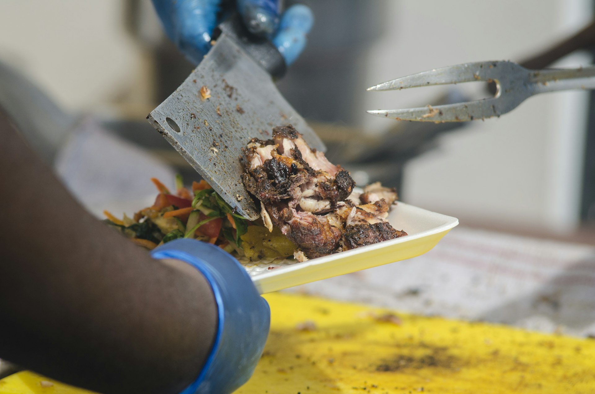 person serving another a plate of jerk chicken