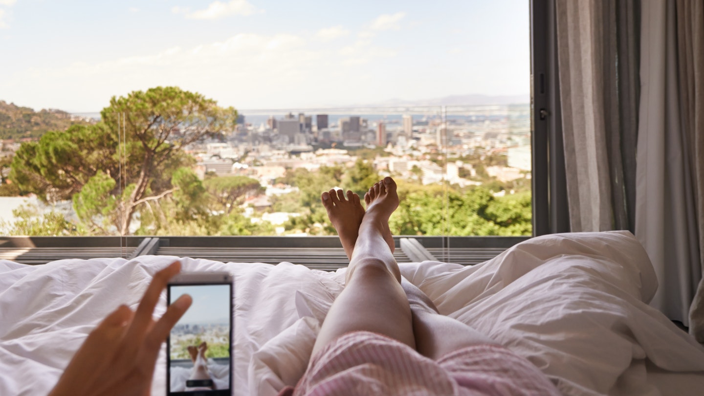 Cropped shot of a woman in bed taking a picture of the view from her bedroom