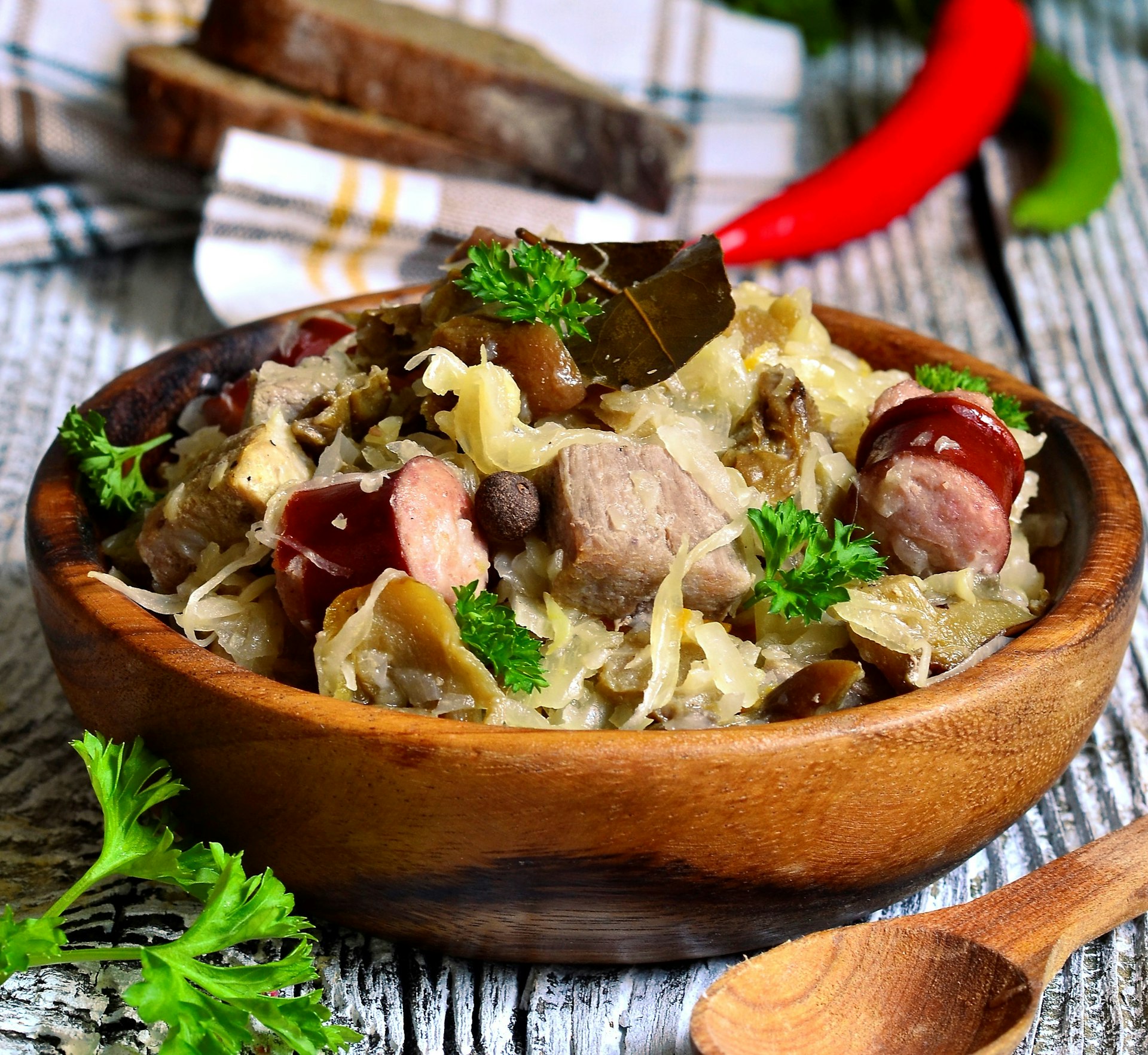 A bowl of Polish bigos from a side on view. The dish contains vegetables and meat in a broth.