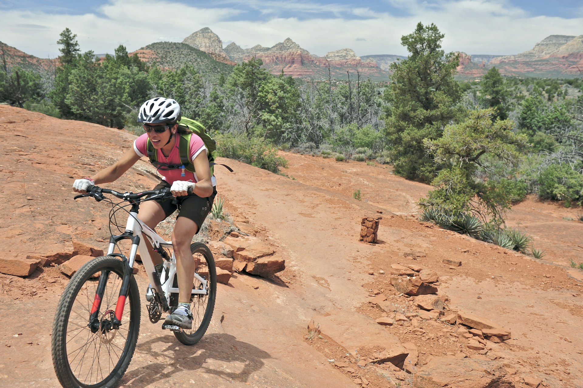 A woman rides a mountain bike on a red stony track with desert landscape stretching out behind her