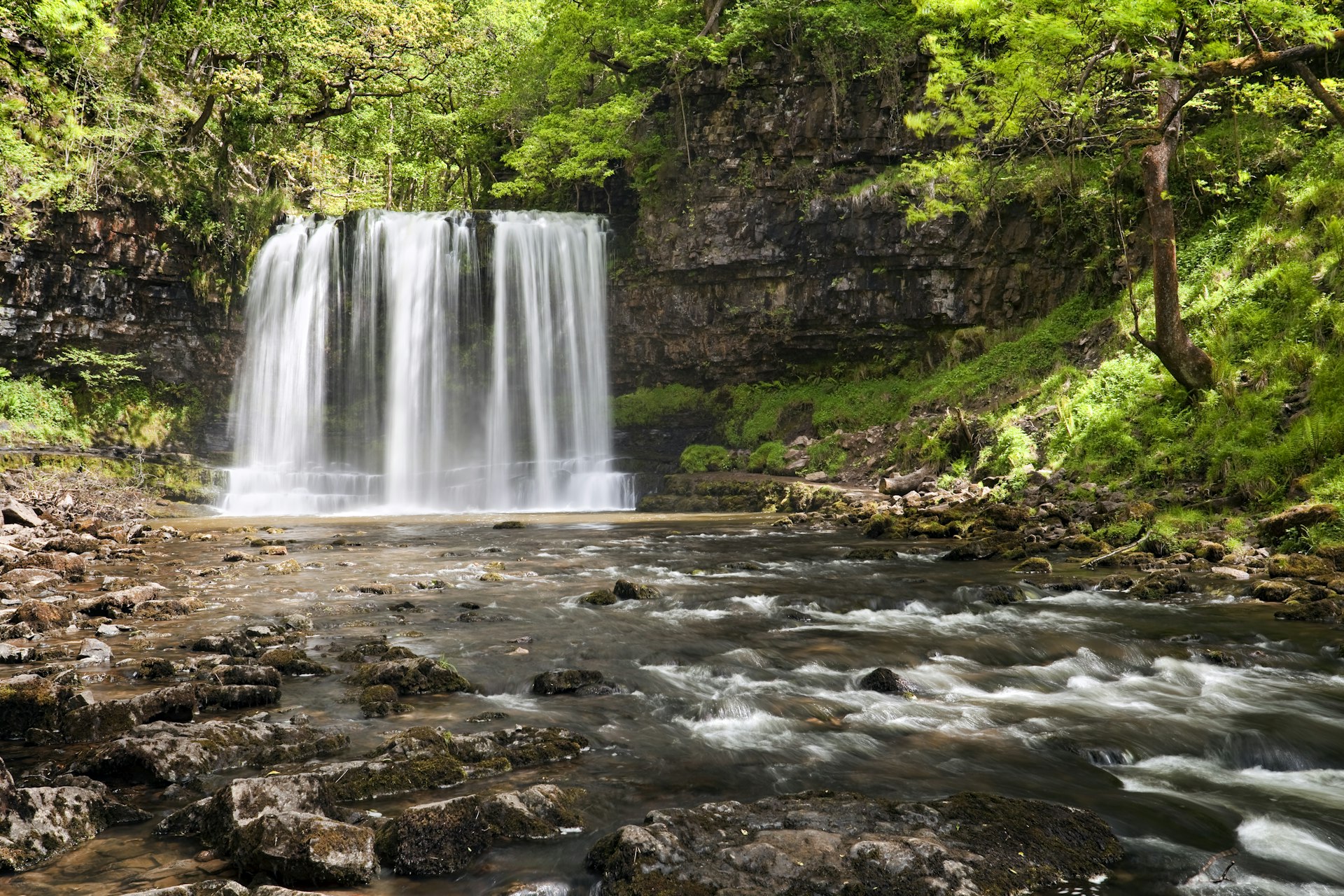 Sgwd yr Eira, a horseshoe waterfall, plunges into a pool