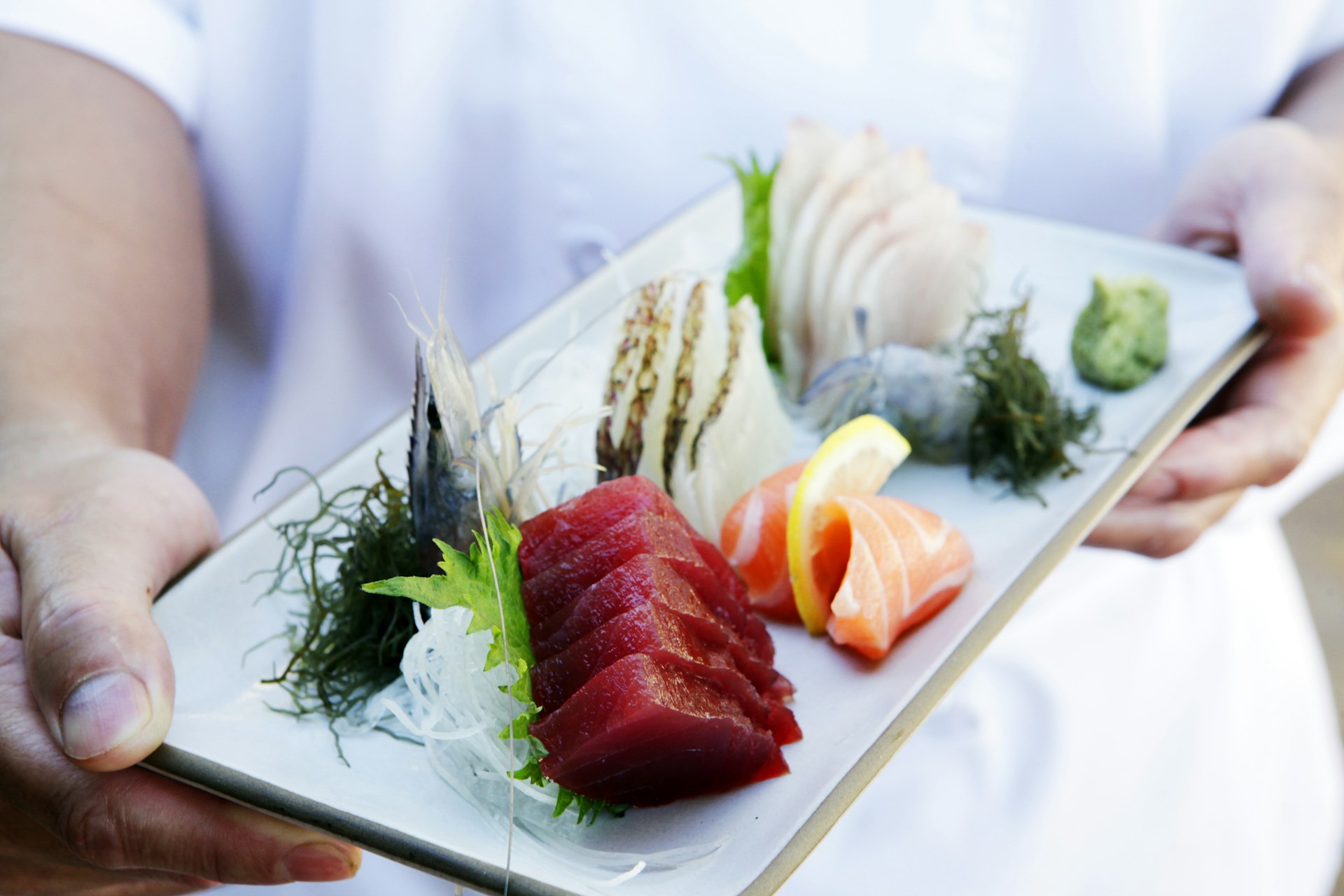 Hands holding tray of fresh sushi