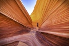 A man stannds on 'The Wave' sandstone rock formation.