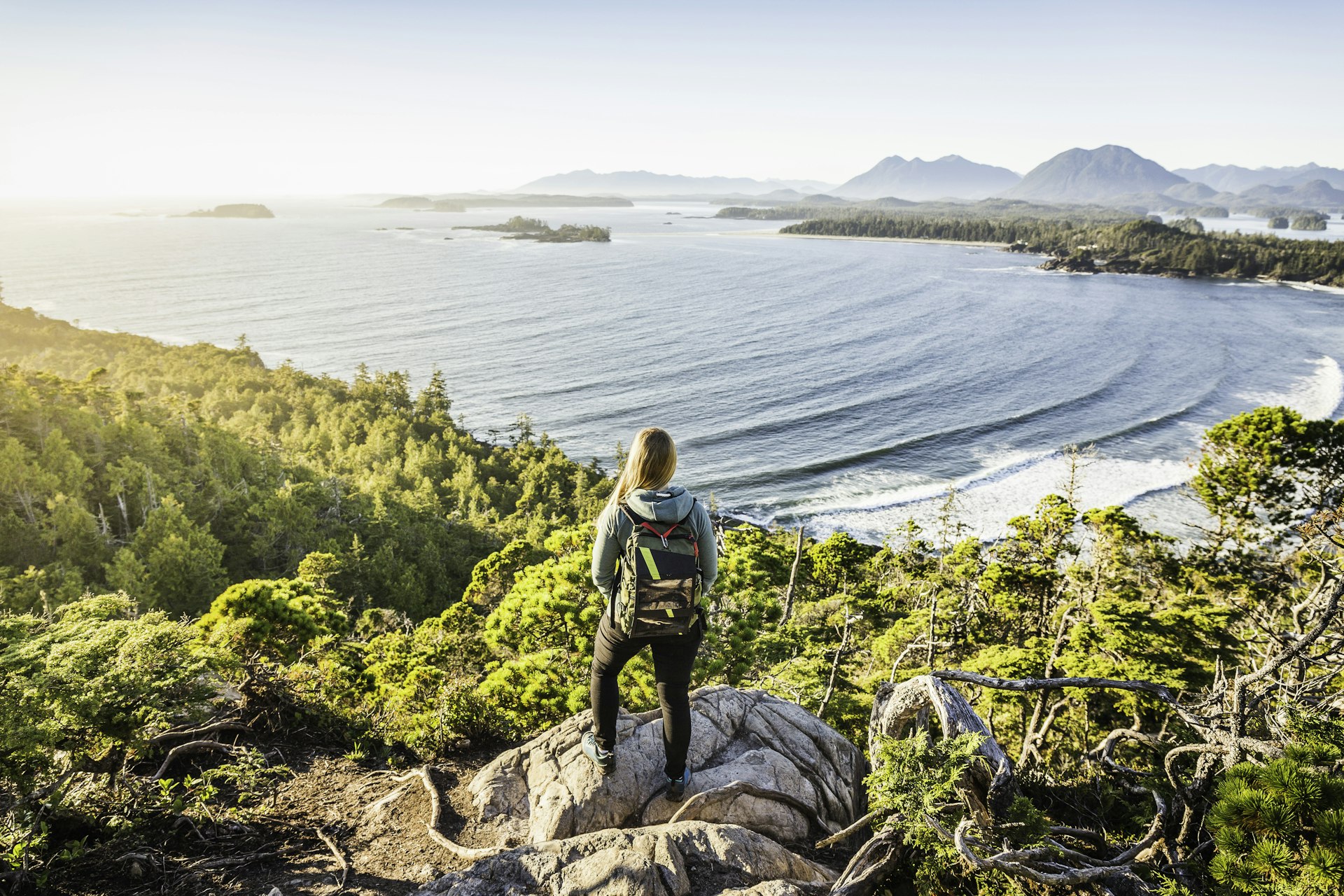 Elevated view of female hiker looking out from coastal forest, Pacific Rim National Park, Vancouver Island, British Columbia, Canada