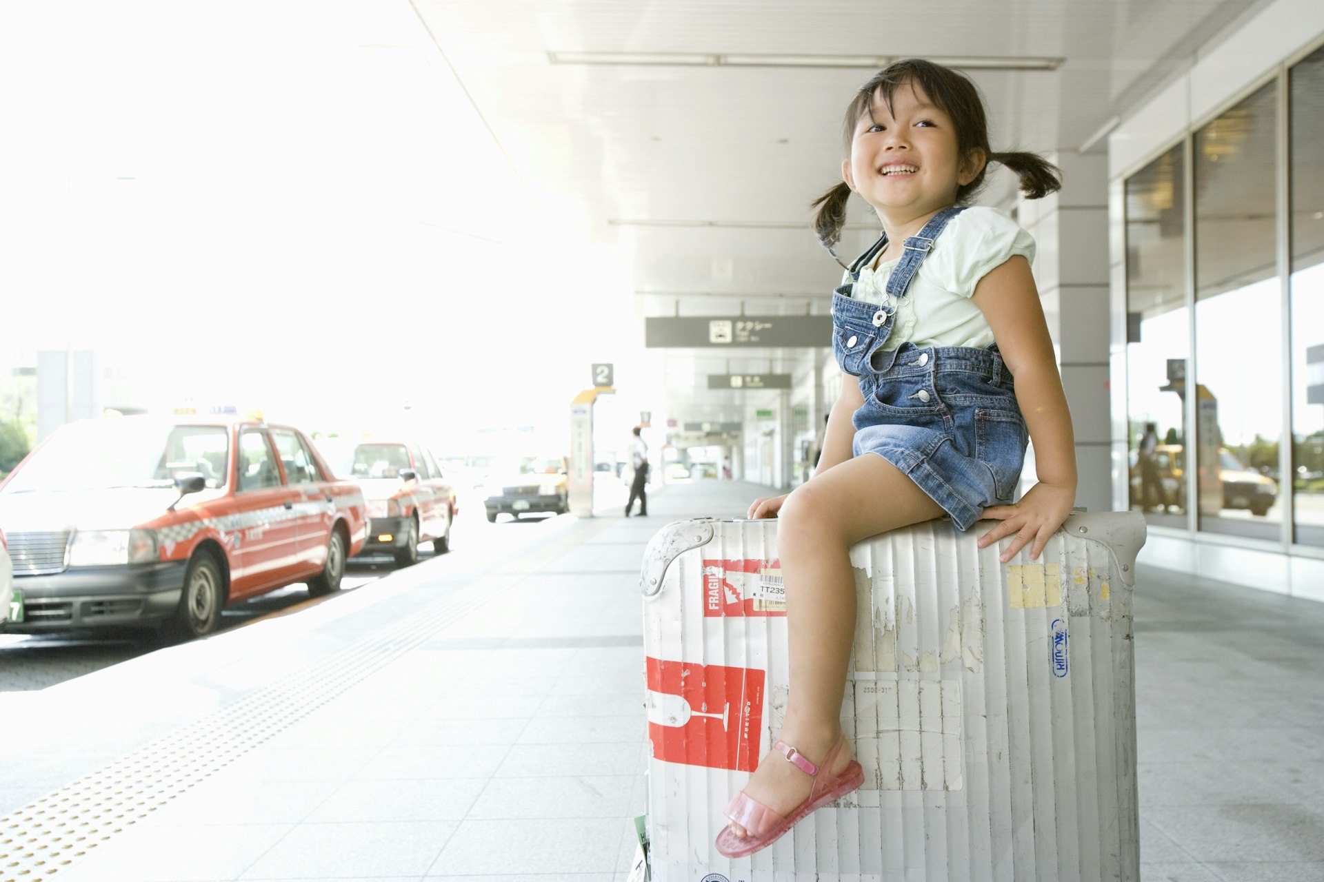A girl rides suitcase by cabstand in airport in Japan 