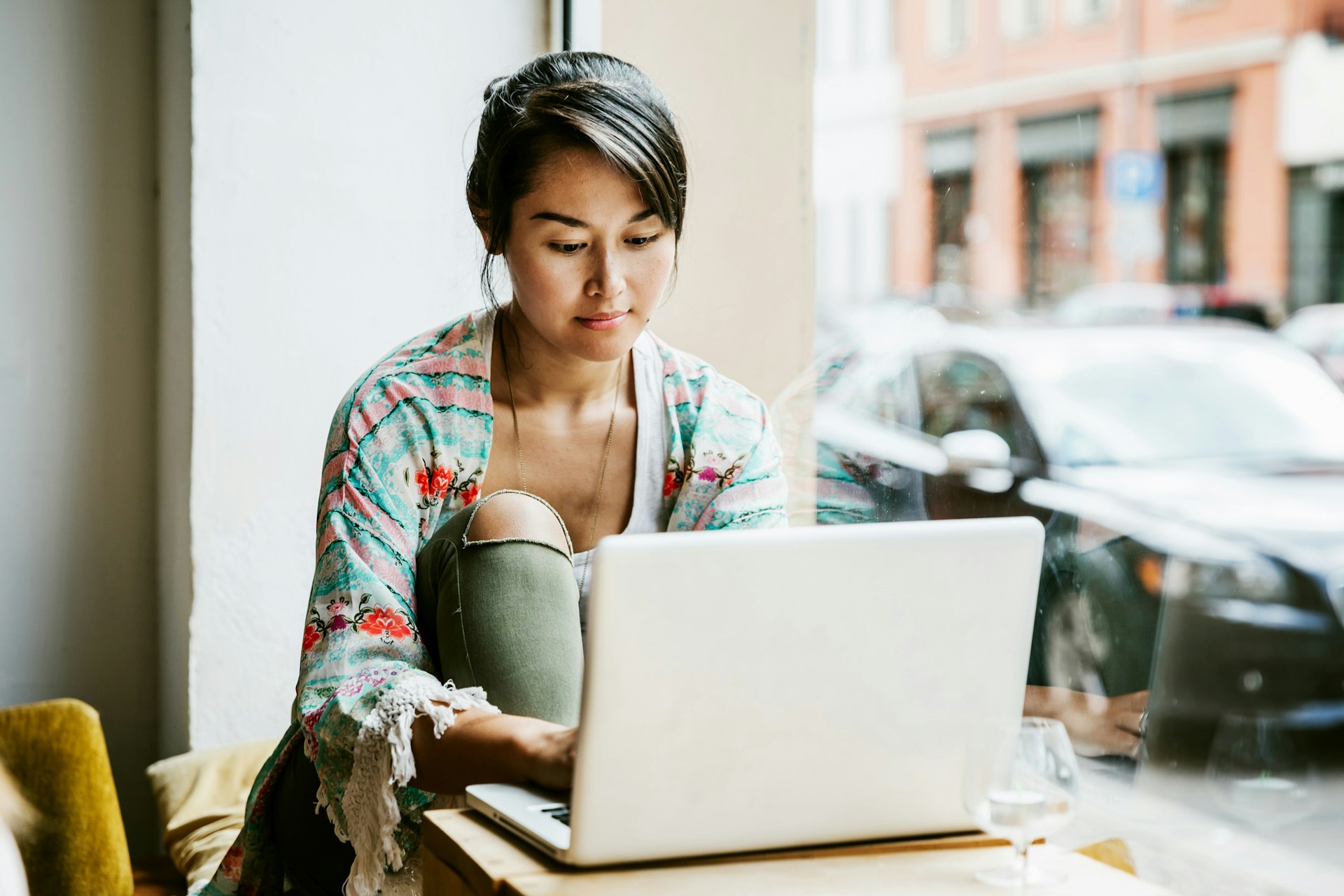 A woman works in a coffee shop on her laptop. 