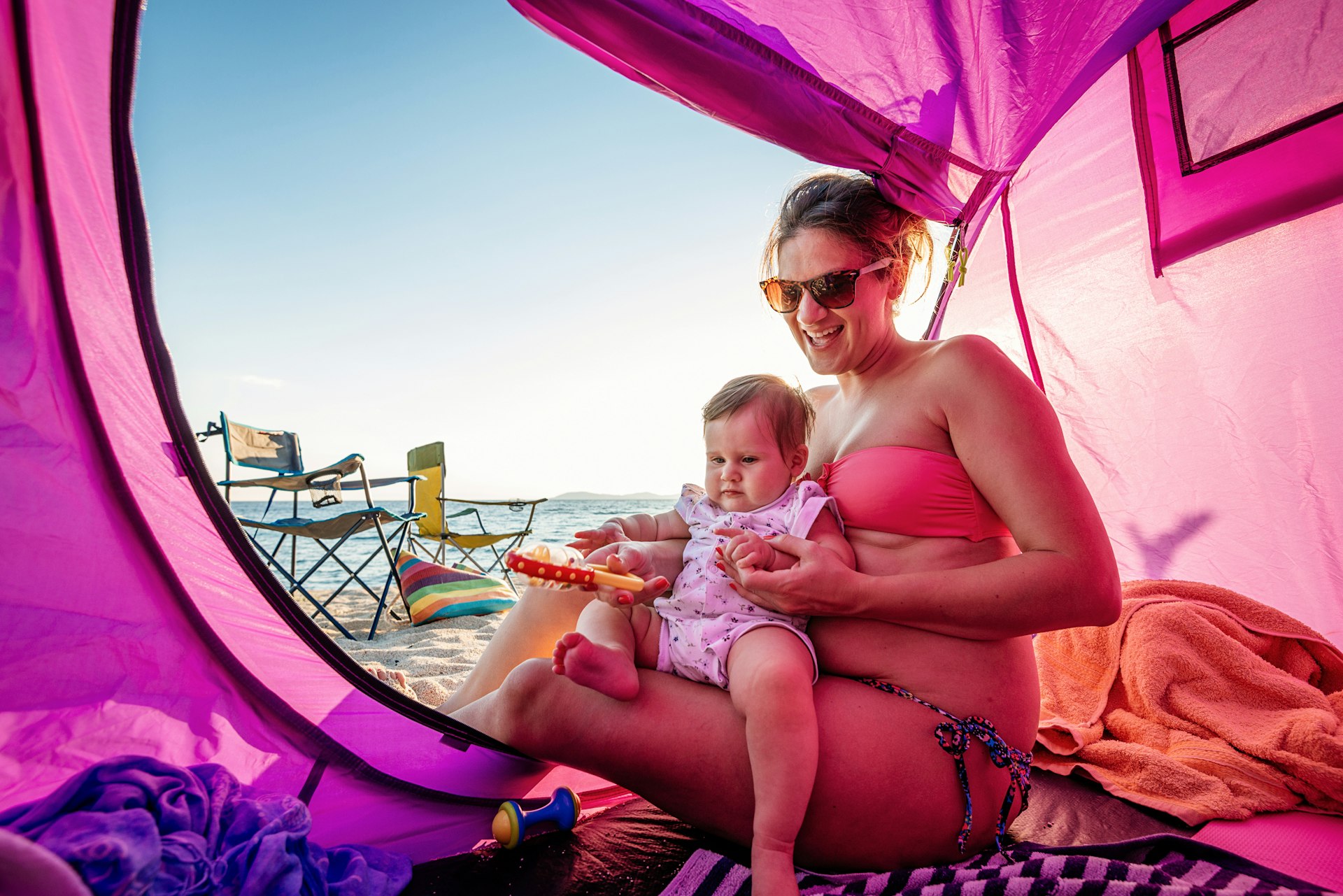 Mother holding her baby in the tent on the beach